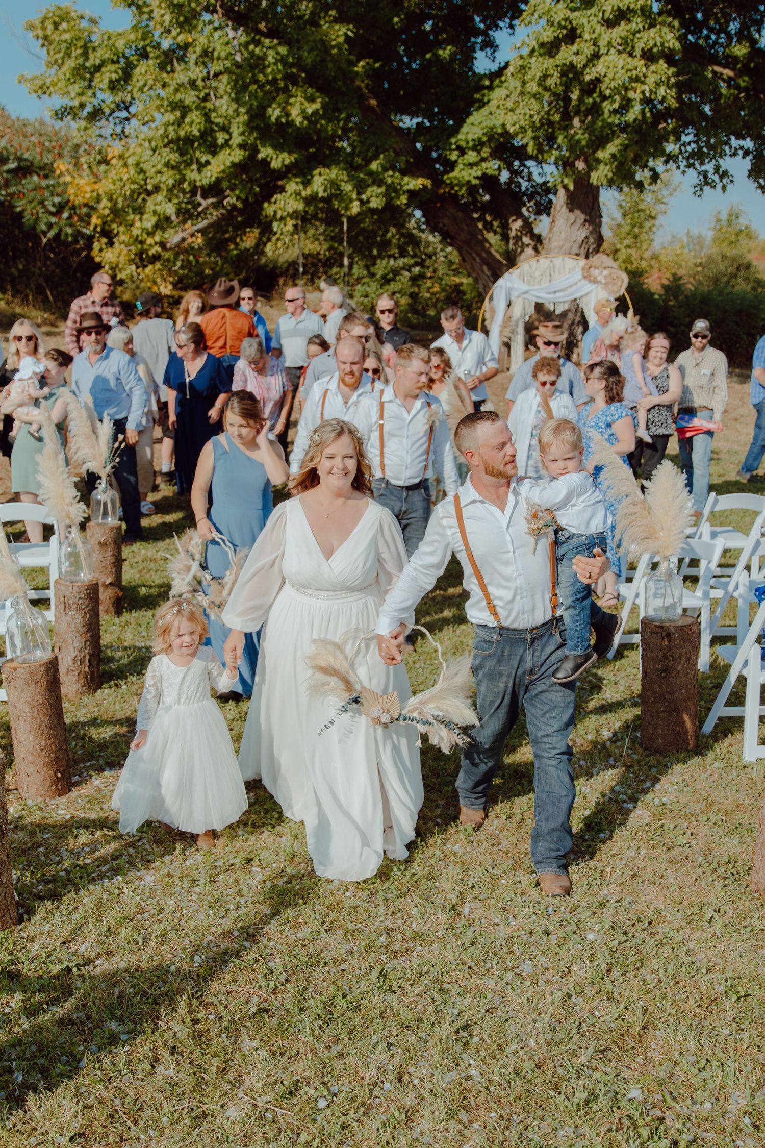 Wedding party and guests celebrating outdoors with joyful expressions.