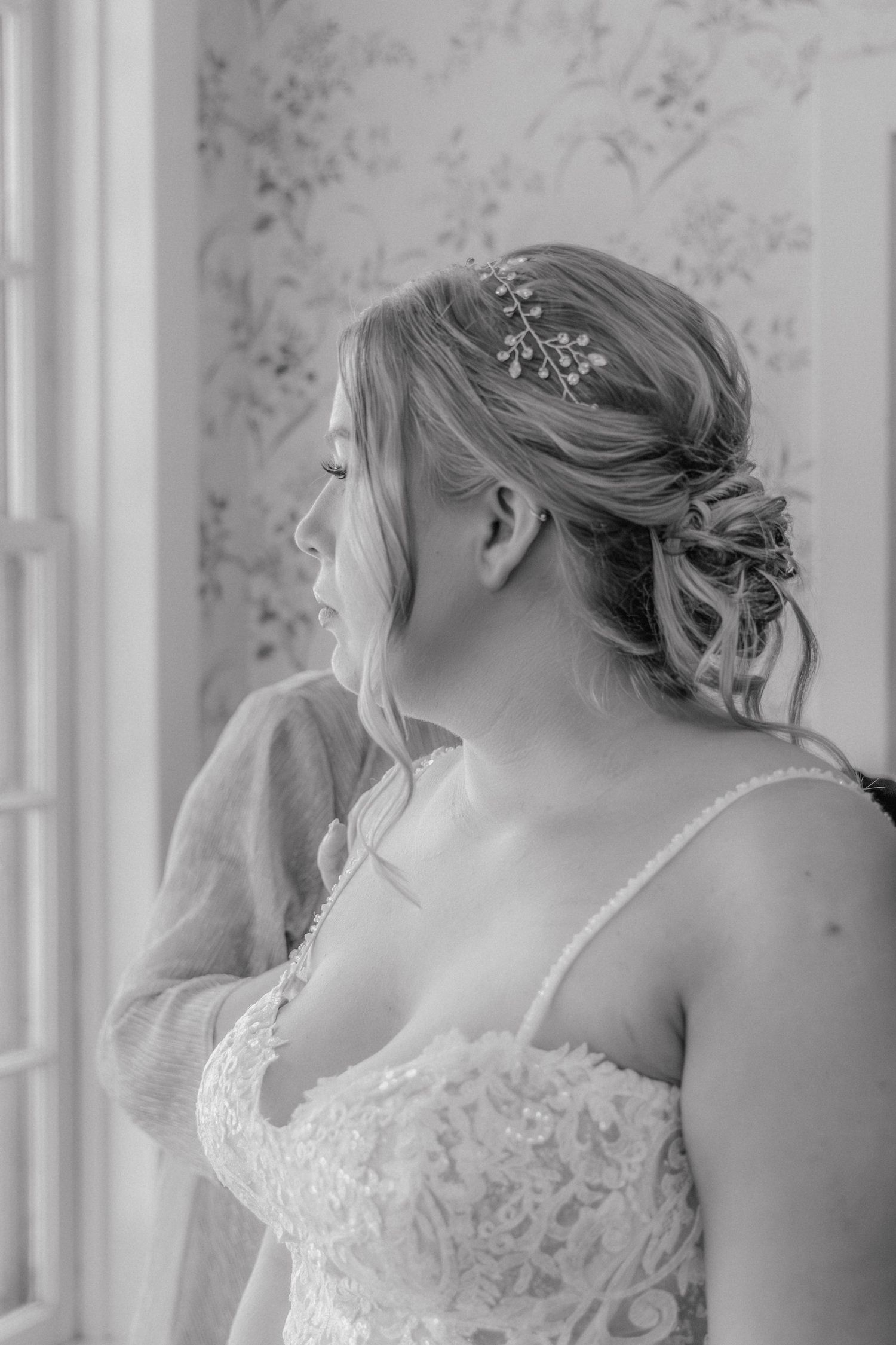 Black and white photo series showing a bride in a lace wedding dress with delicate pearl details and romantic updo hairstyle.