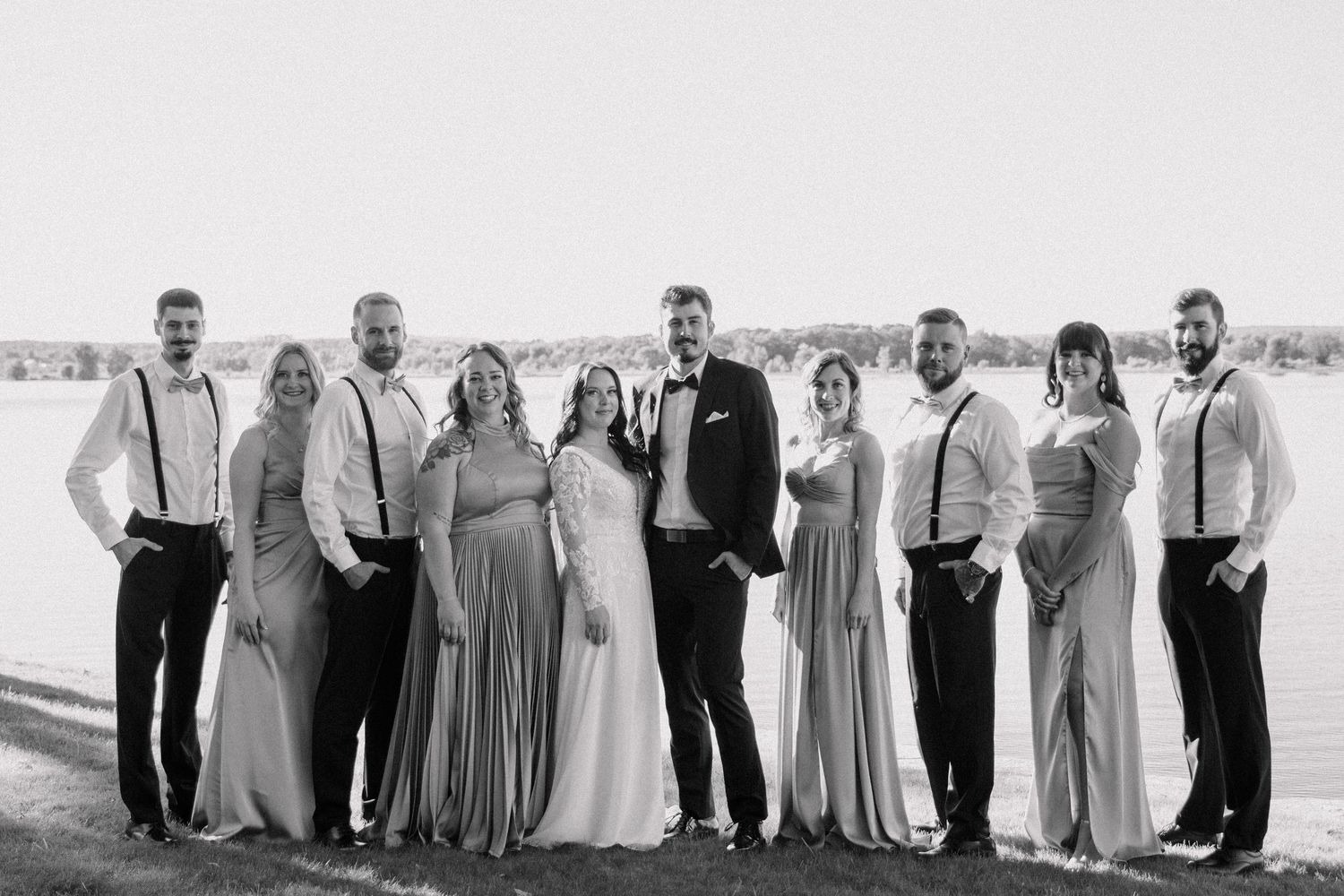 Wedding party lined up outdoors wearing coordinated formal attire in pale colors.