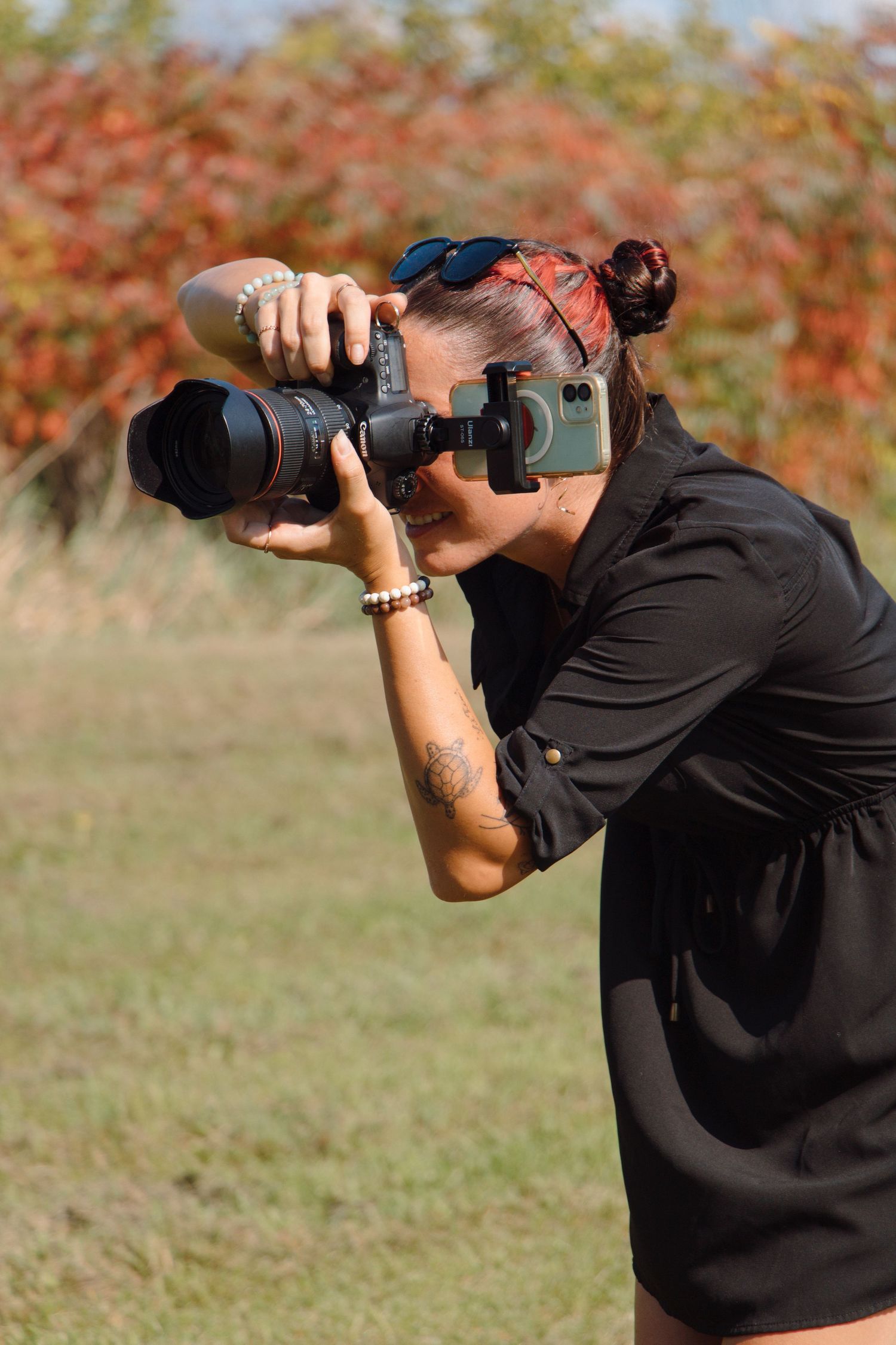 Photographer in black shirt taking photos with professional camera equipment.