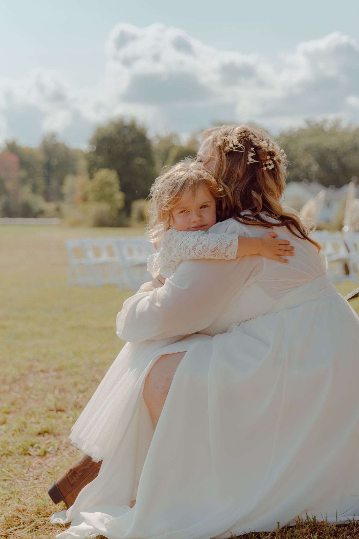 Sun-lit sequence of children in white dresses hugging in a field.