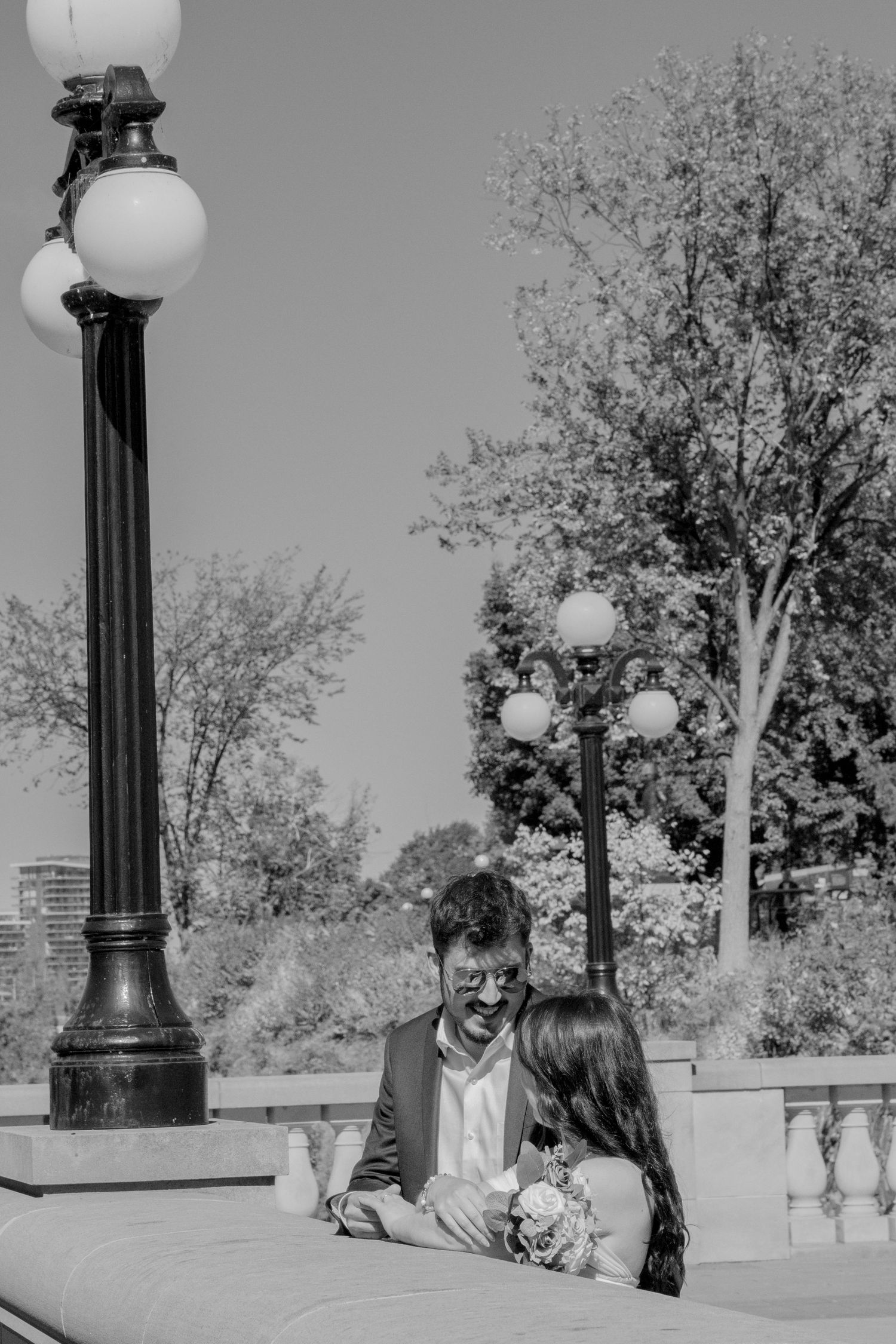 Wedding couple poses together on a terrace with ornate lamp posts.