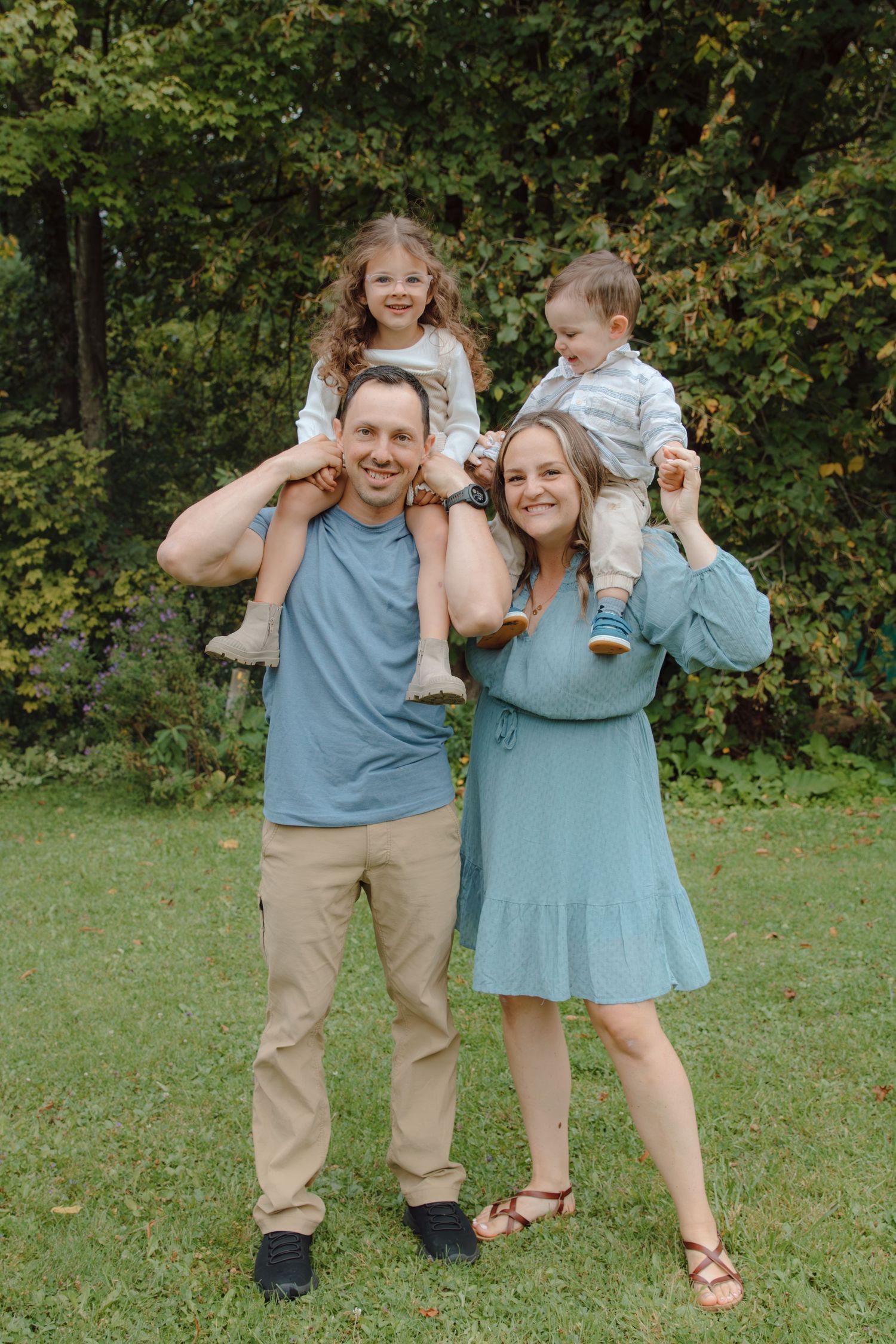 Parents give their children shoulder rides during a fun outdoor photo session.