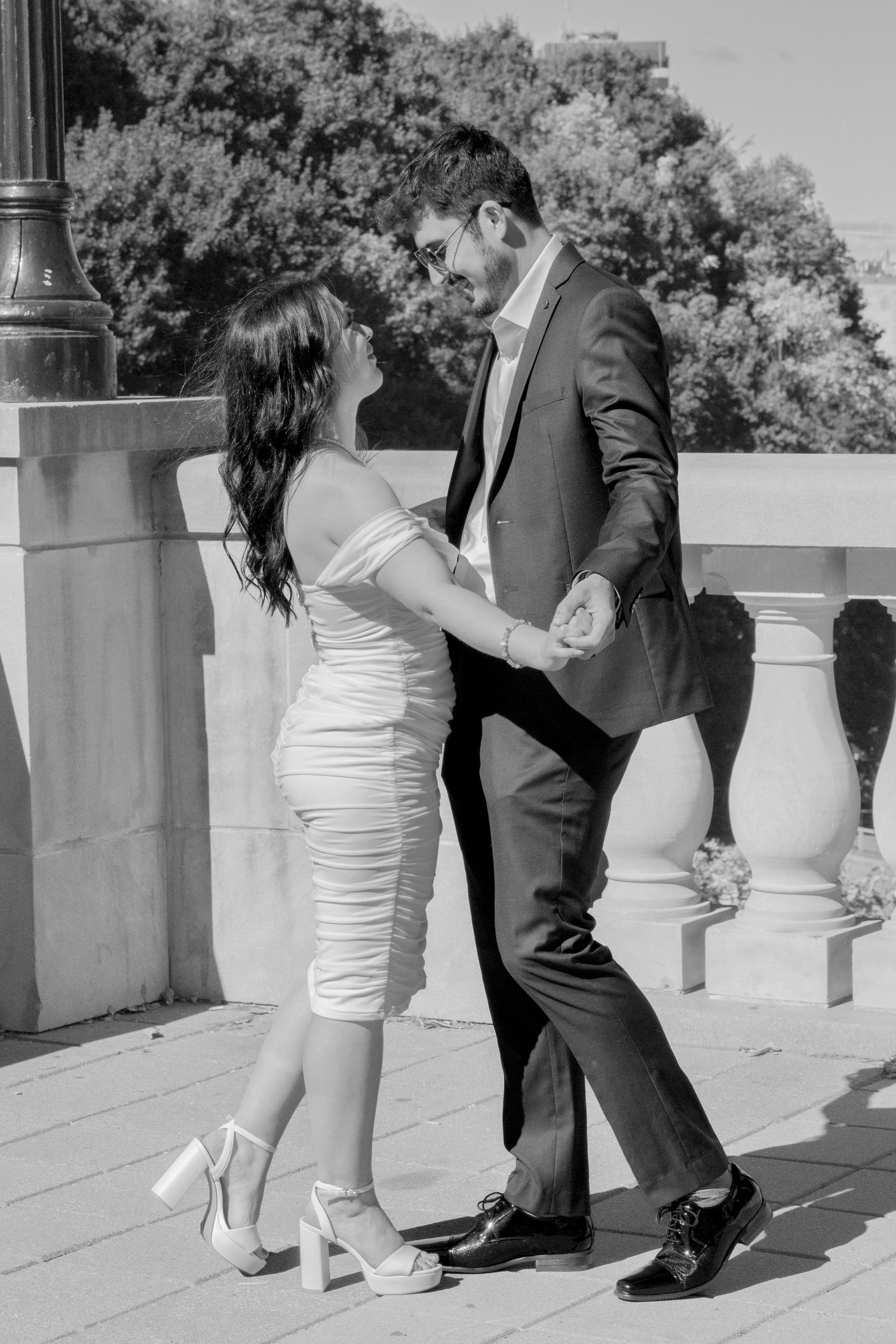 Wedding couple dances together on a terrace with decorative stone railings.