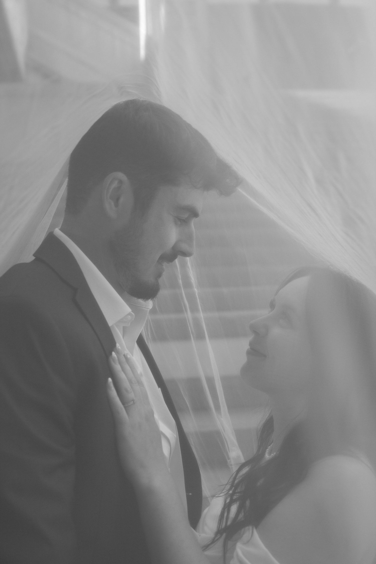 Intimate black and white portraits of newlyweds beneath sheer veil.