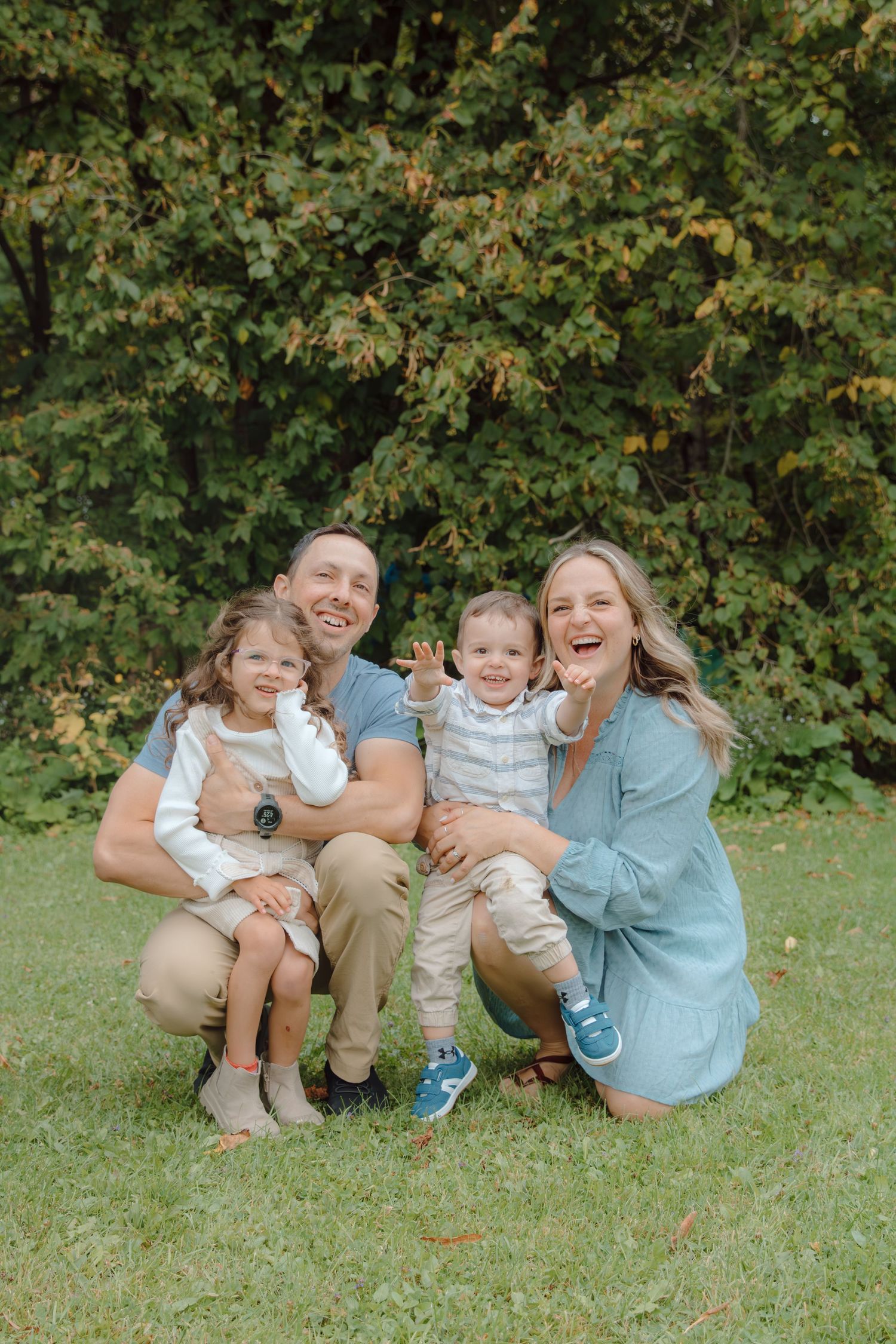A candid family photo showing genuine laughter and joy in a natural outdoor setting.