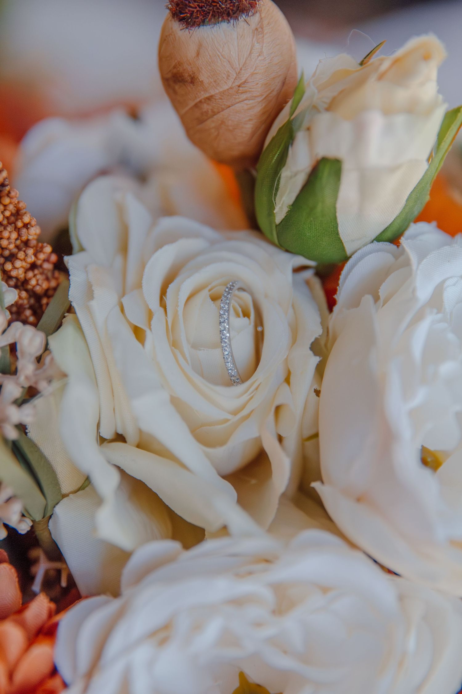 Wedding ring nestled in delicate white rose petals with soft bokeh background.