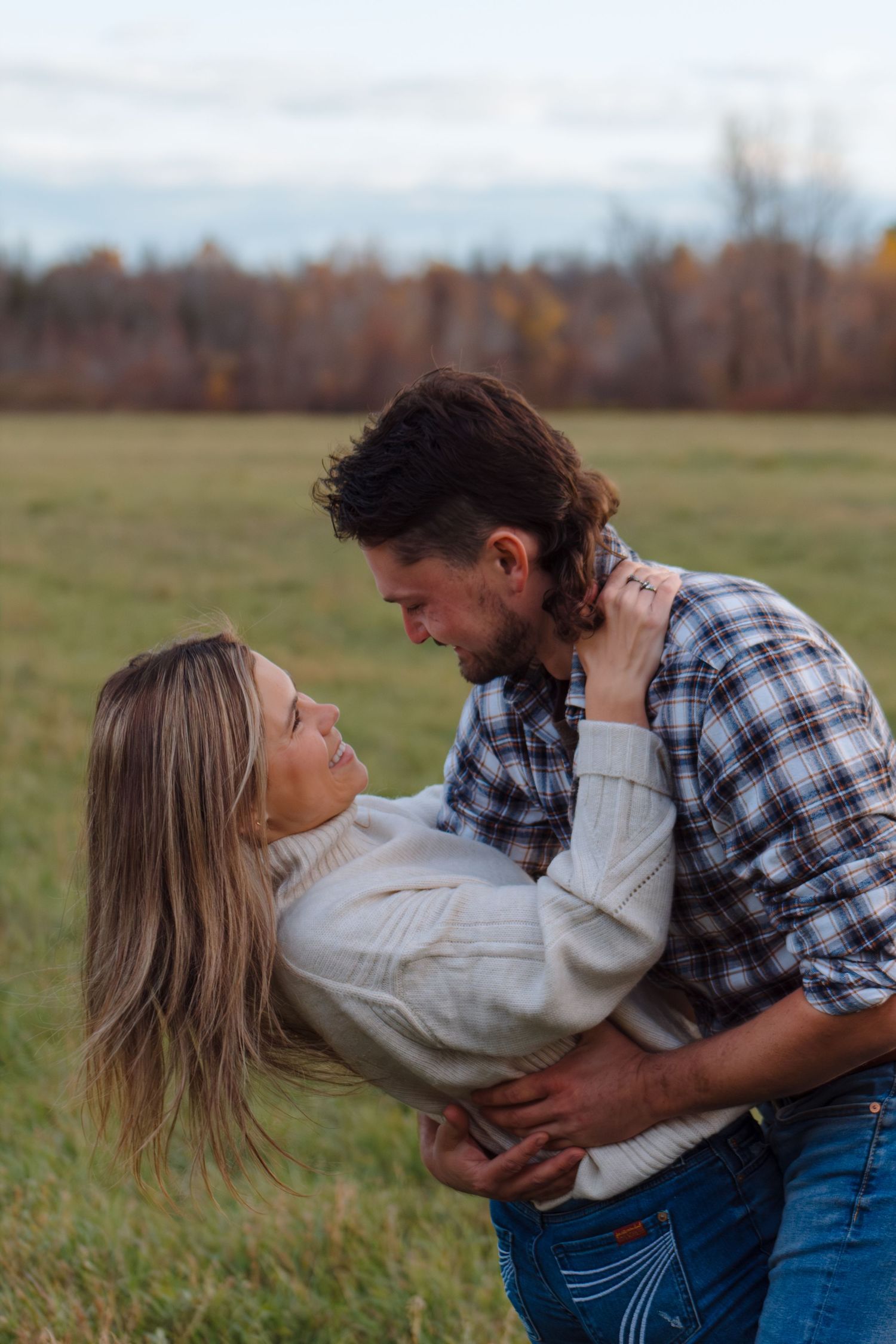 A couple performs a romantic dance dip in a rustic field setting.