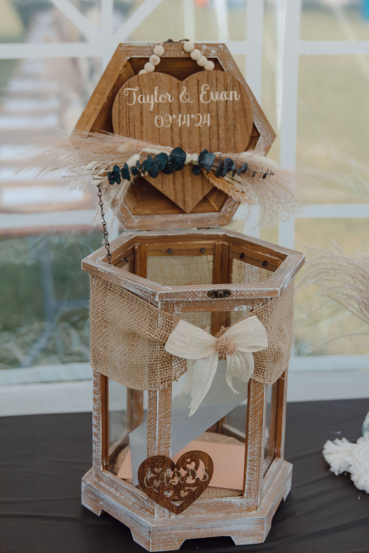 Rustic wooden hexagonal lantern decorated with burlap, white bow and heart details for a wedding.