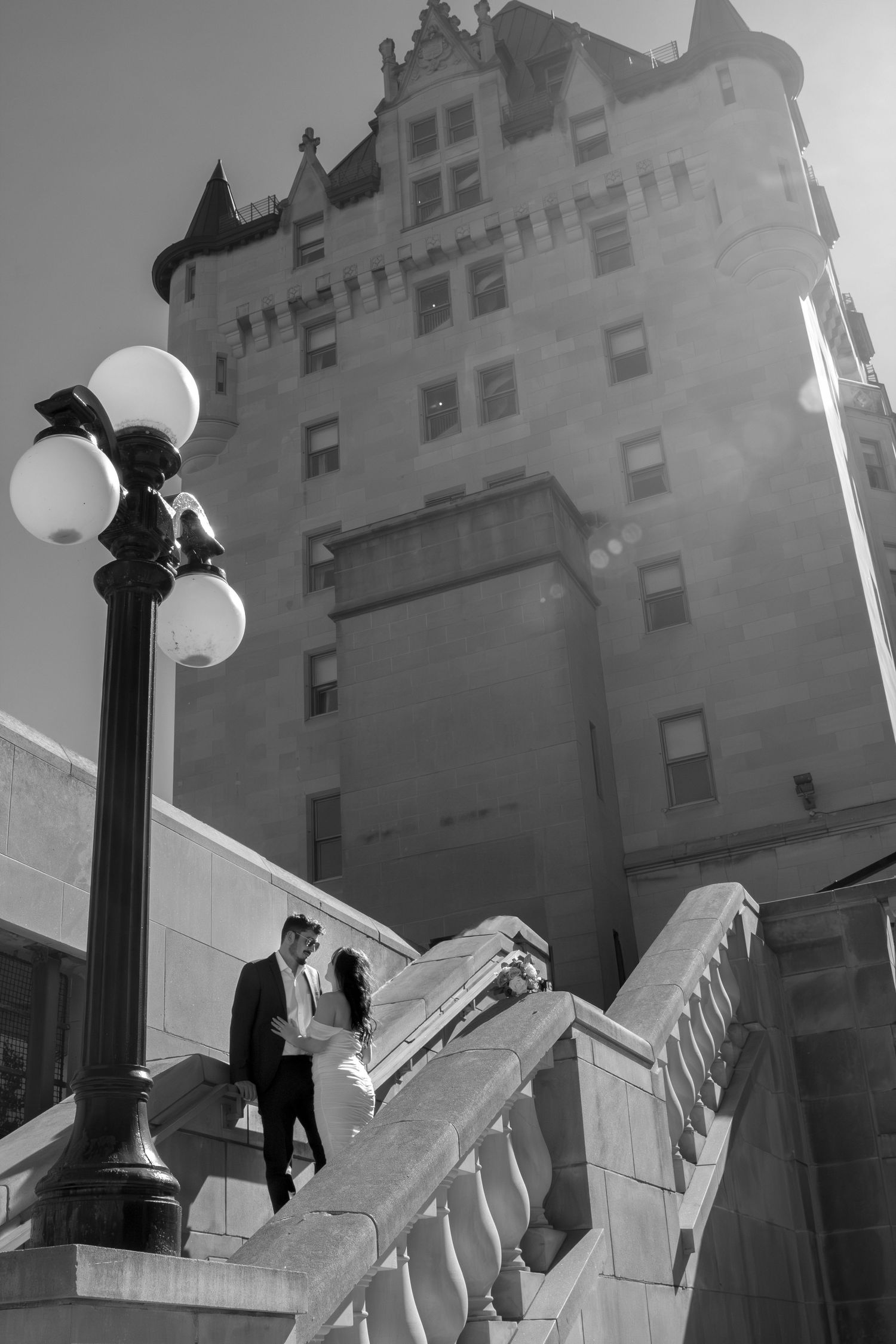 Architectural sequence showing a couple against a building facade with ornate lamp posts.