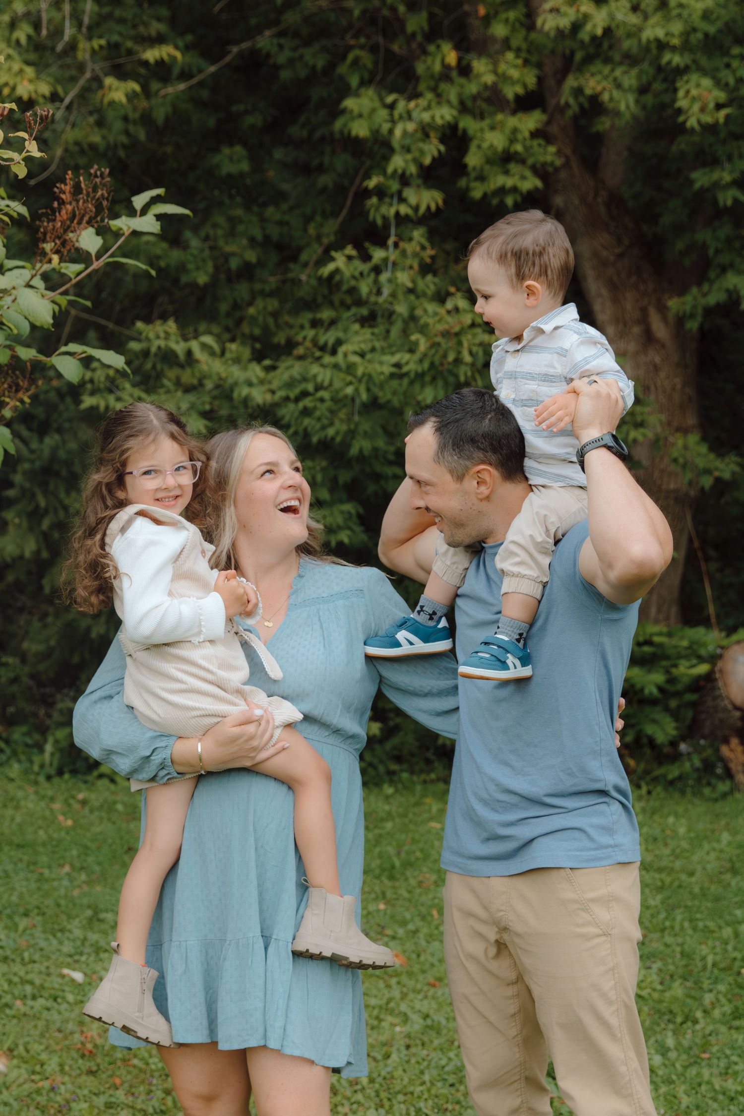 A joyful family moment captured outdoors with parents lifting their children in a playful pose.