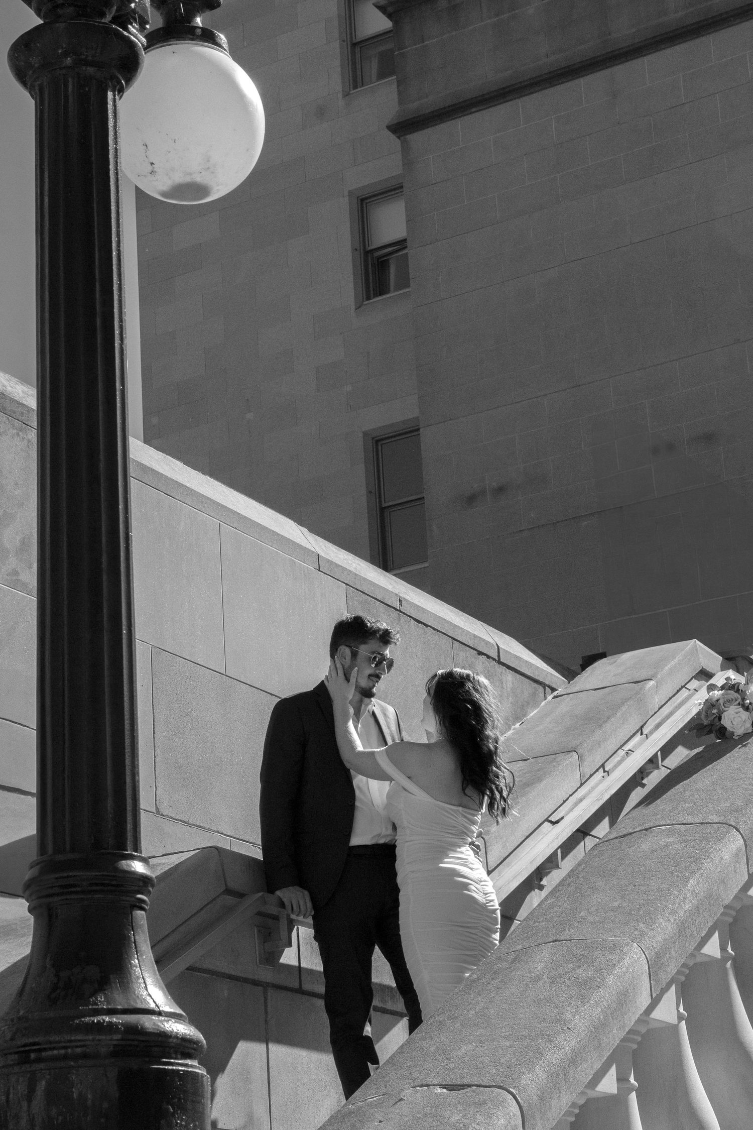 Couple shares a romantic moment on an architectural terrace in black and white.