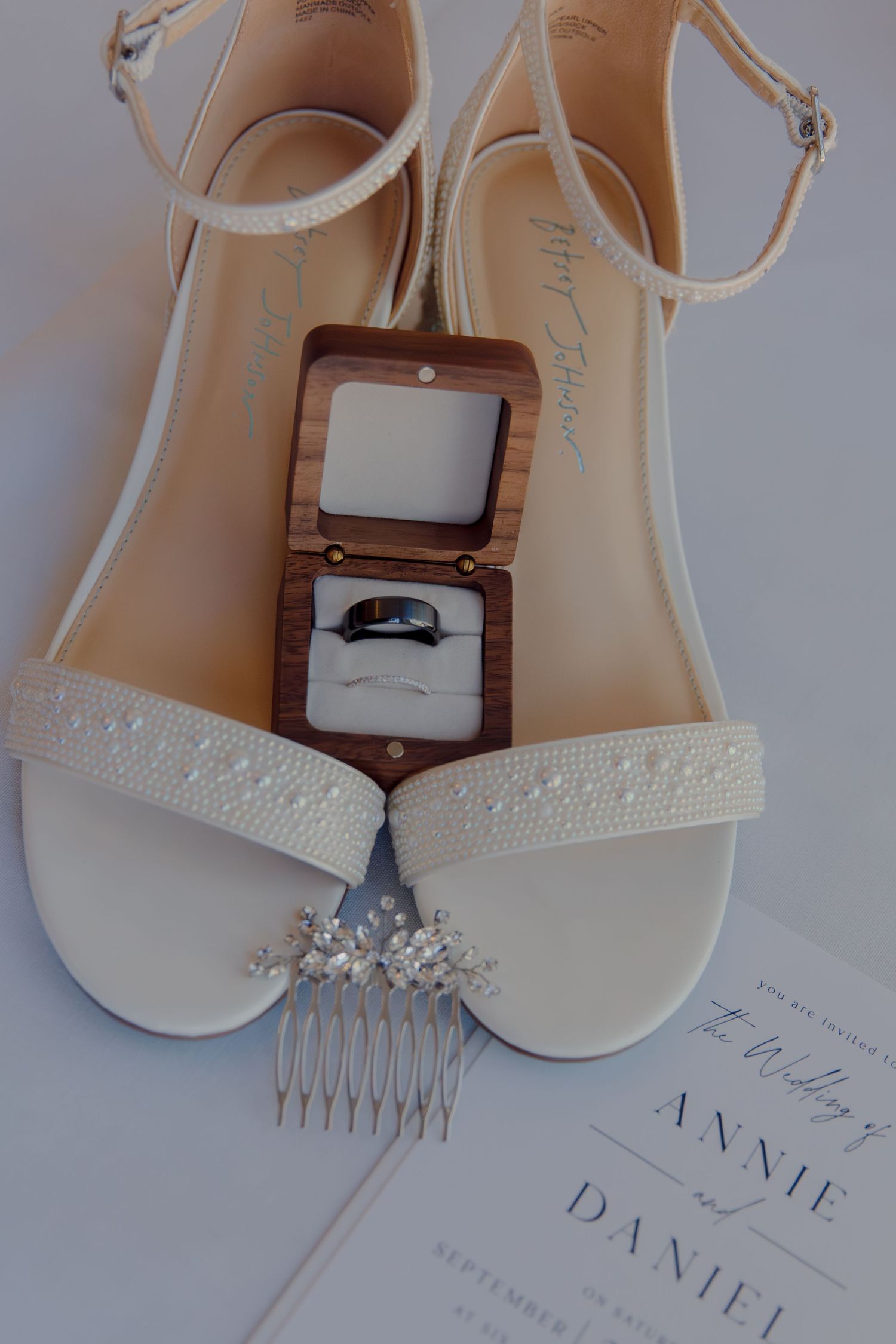 Wedding accessories including white bridal shoes, hair combs and invitation details.