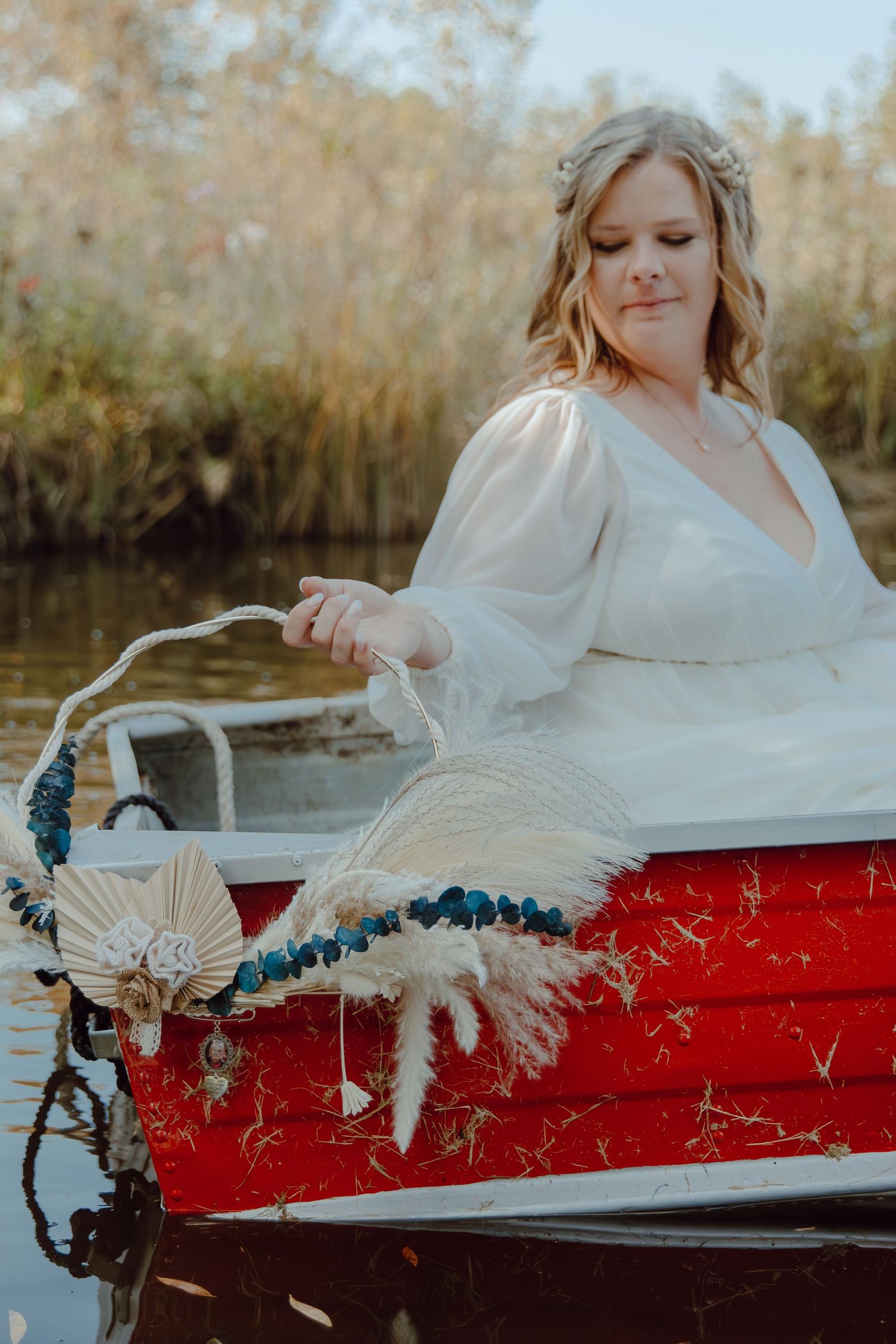 A person in white dress reclines in a vintage red boat on calm waters.