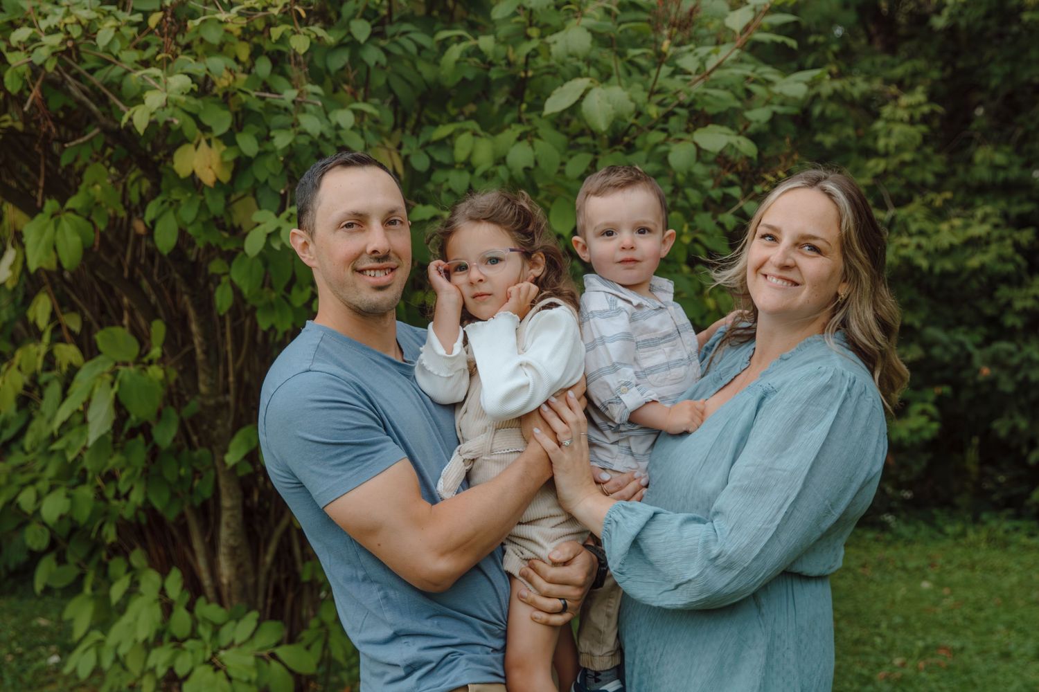 A family in coordinating blue and white outfits shares tender moments outdoors.