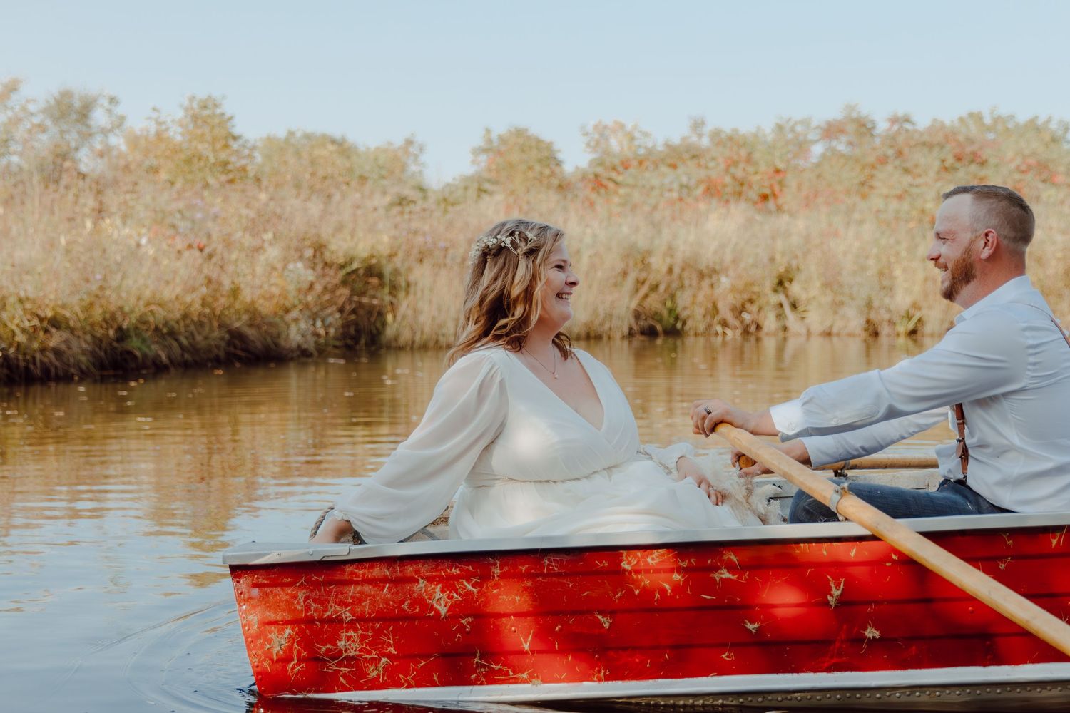 A couple enjoys a peaceful moment together in a red canoe on calm waters.