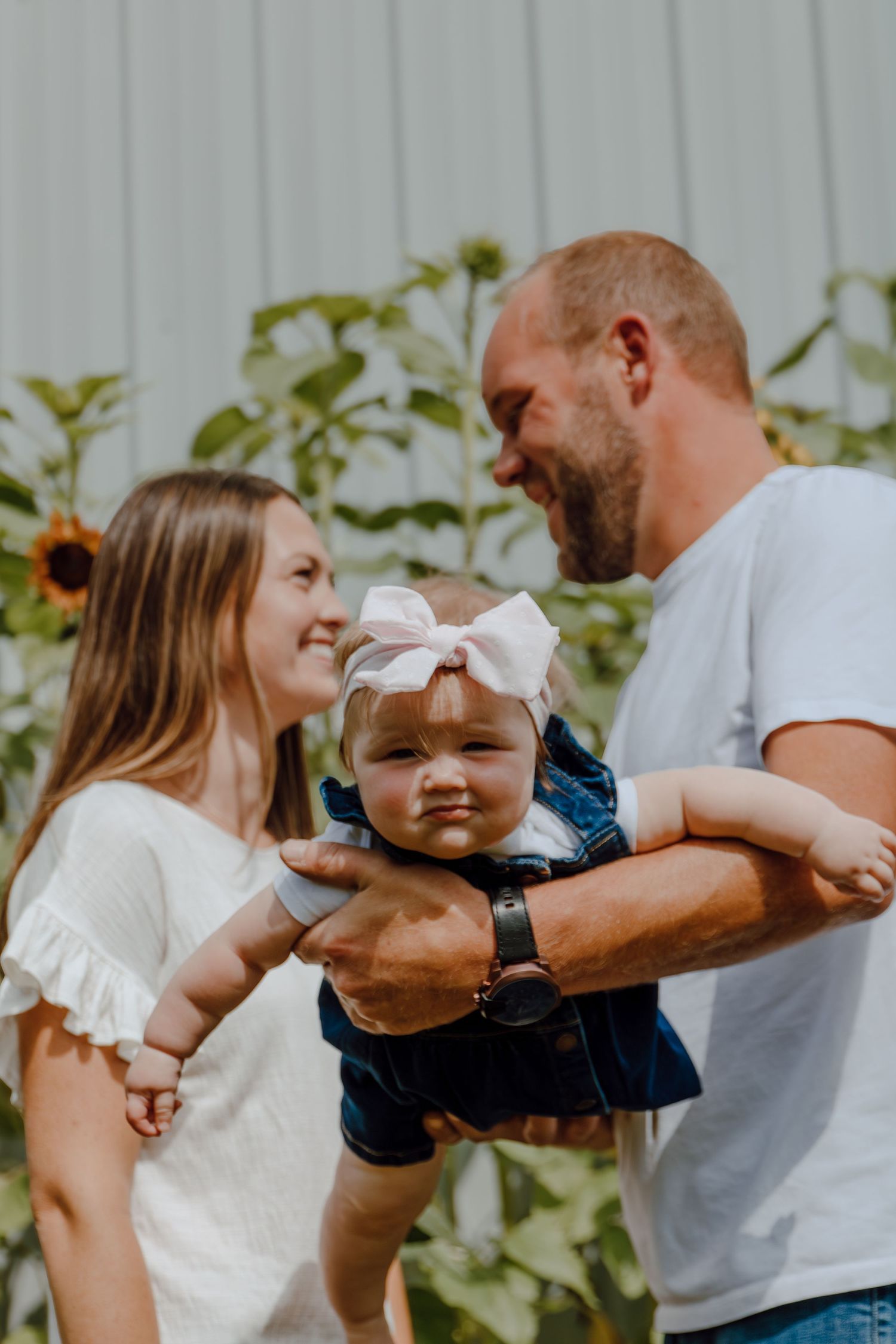Family having fun together outdoors against a grey wall with sunflowers.