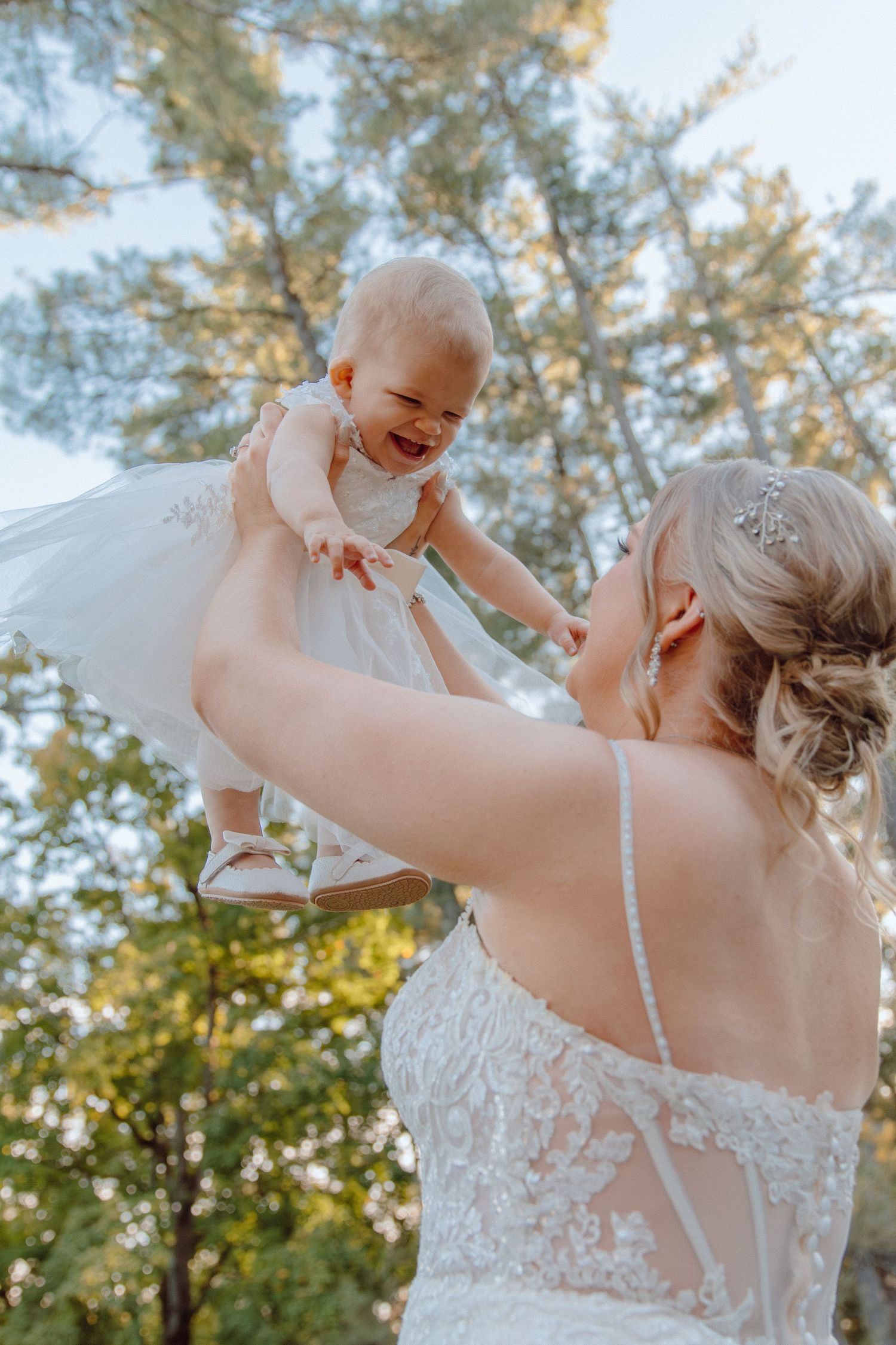 A joyful wedding moment captured in a series showing a bride lifting a small child outdoors.