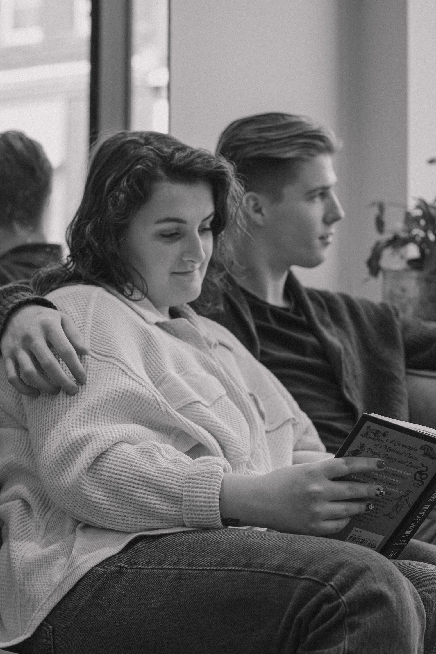 Two people relax together on a couch while using digital devices.