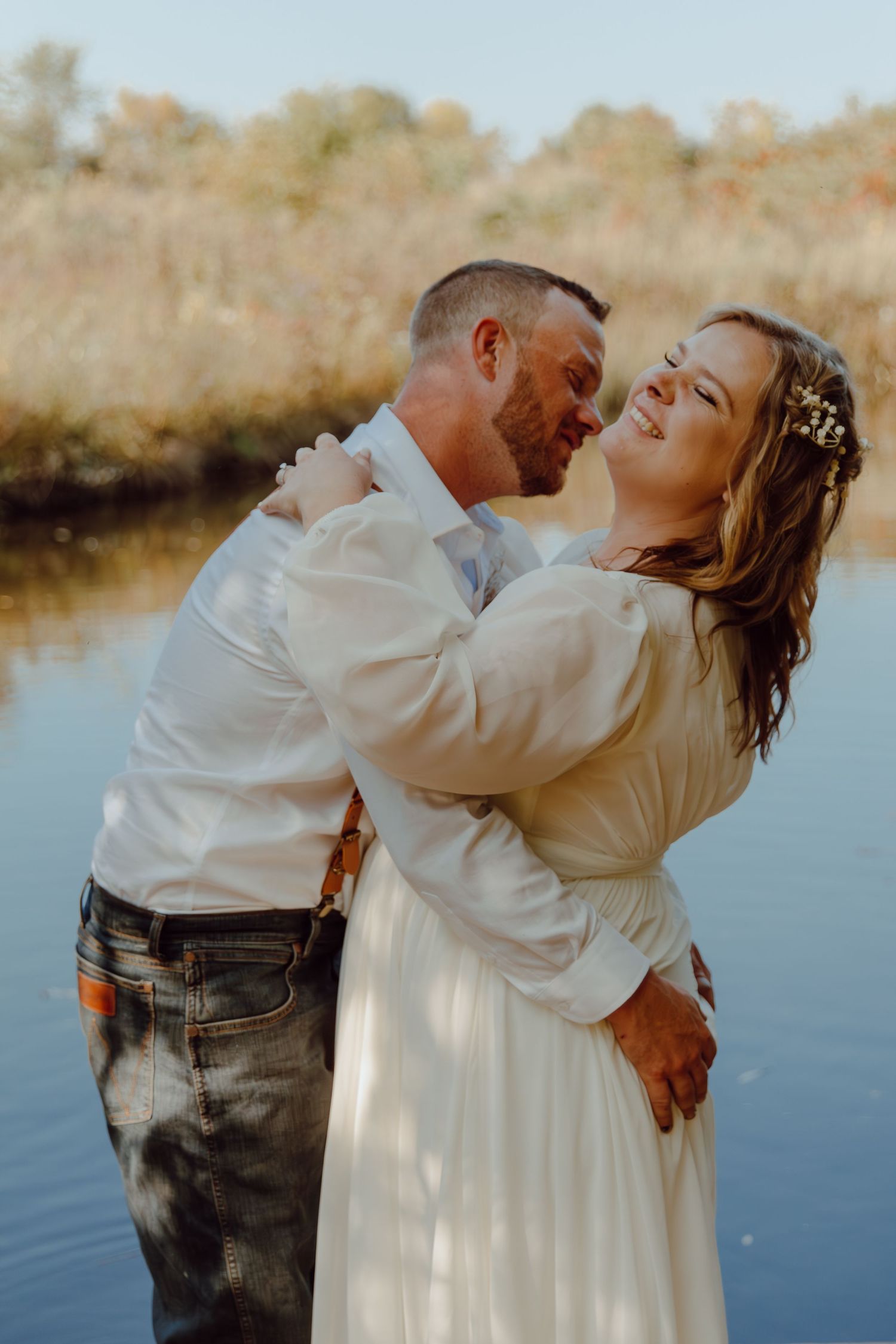 A romantic couple embraces by a lake during their wedding photoshoot.