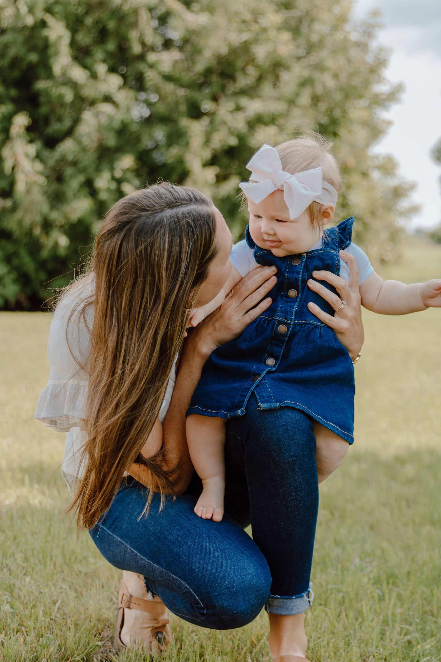 Mother and baby sharing tender moments together in a grassy field.