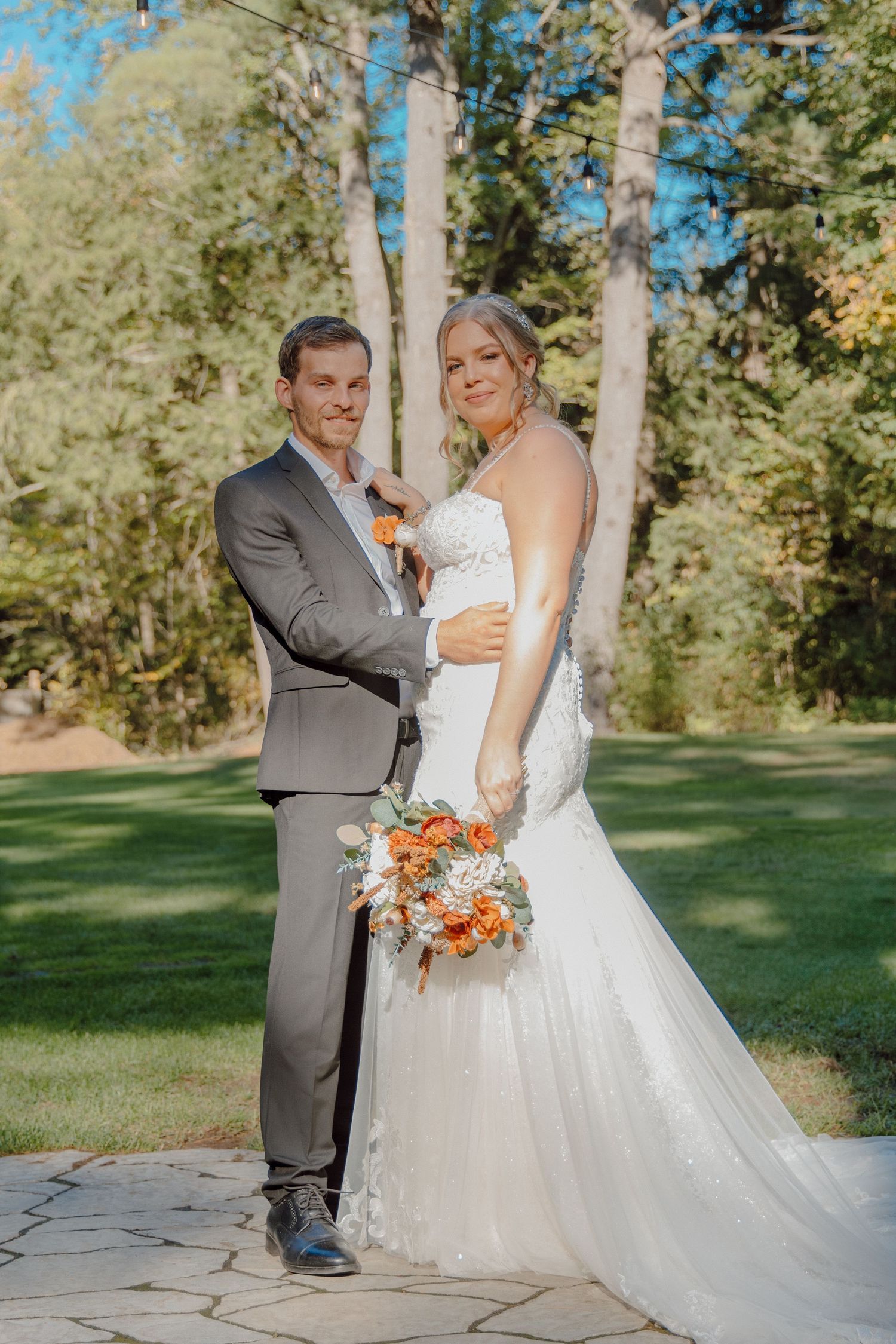 Wedding couple in outdoor setting with autumn trees and white dress.