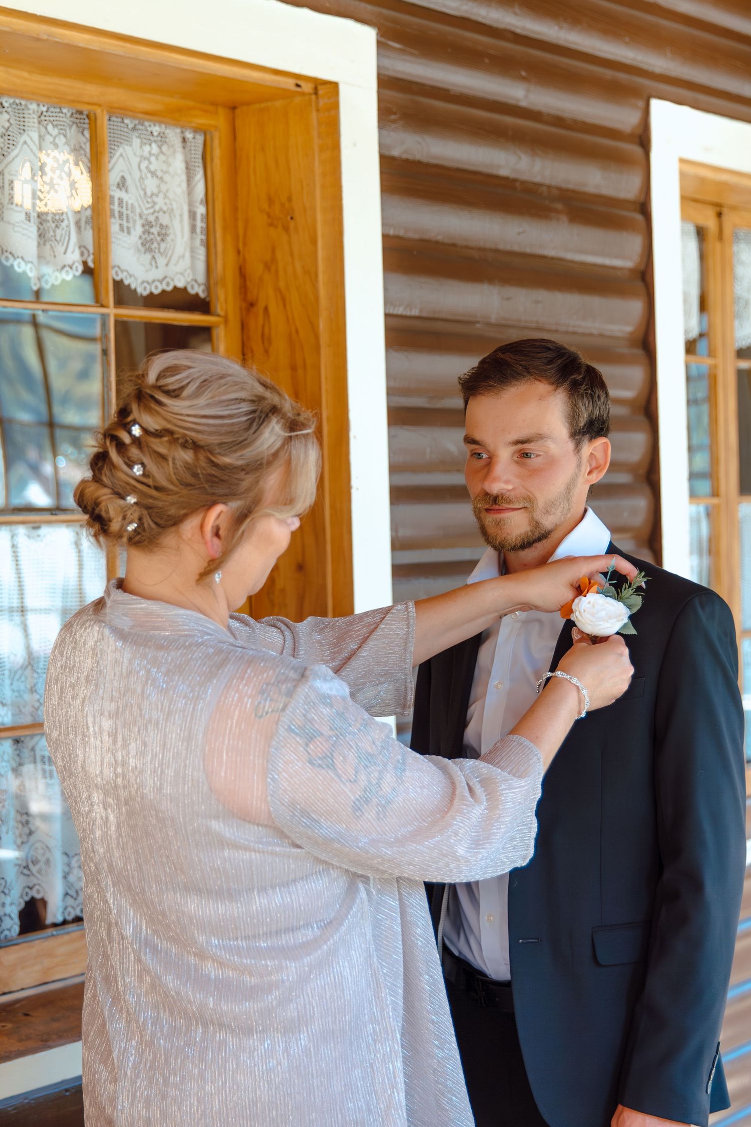A sequence showing a wedding preparation moment as a boutonniere is pinned onto a black suit.