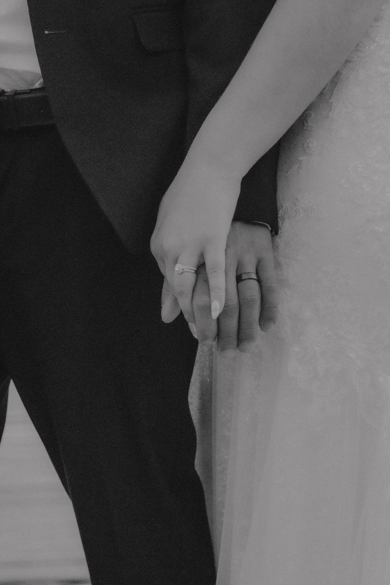 A black and white close-up of two hands wearing wedding rings, symbolizing marriage and commitment.