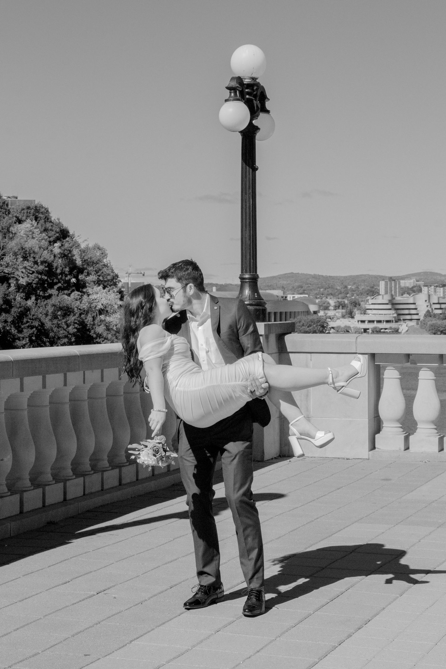 Couple playfully dips and dances on an outdoor terrace with stone railings.