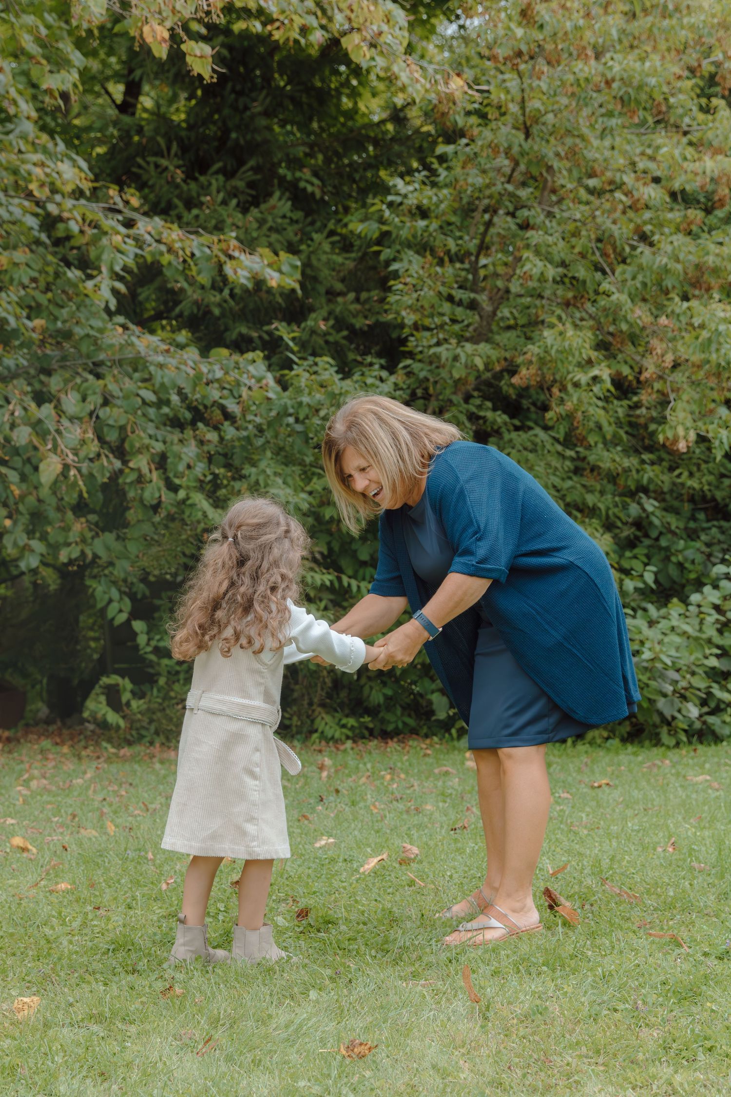A heartwarming sequence of playful interaction between two people in a grassy outdoor setting with trees in the background.