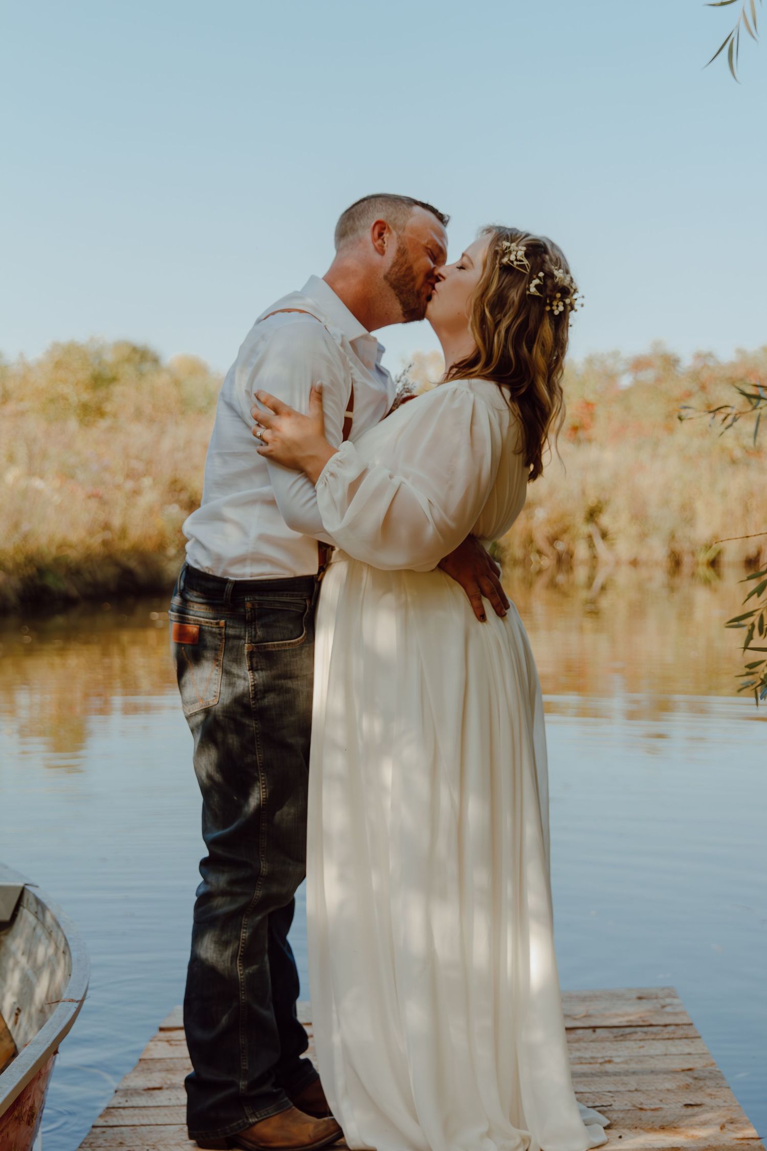 A couple shares an intimate moment on a wooden dock by the water.