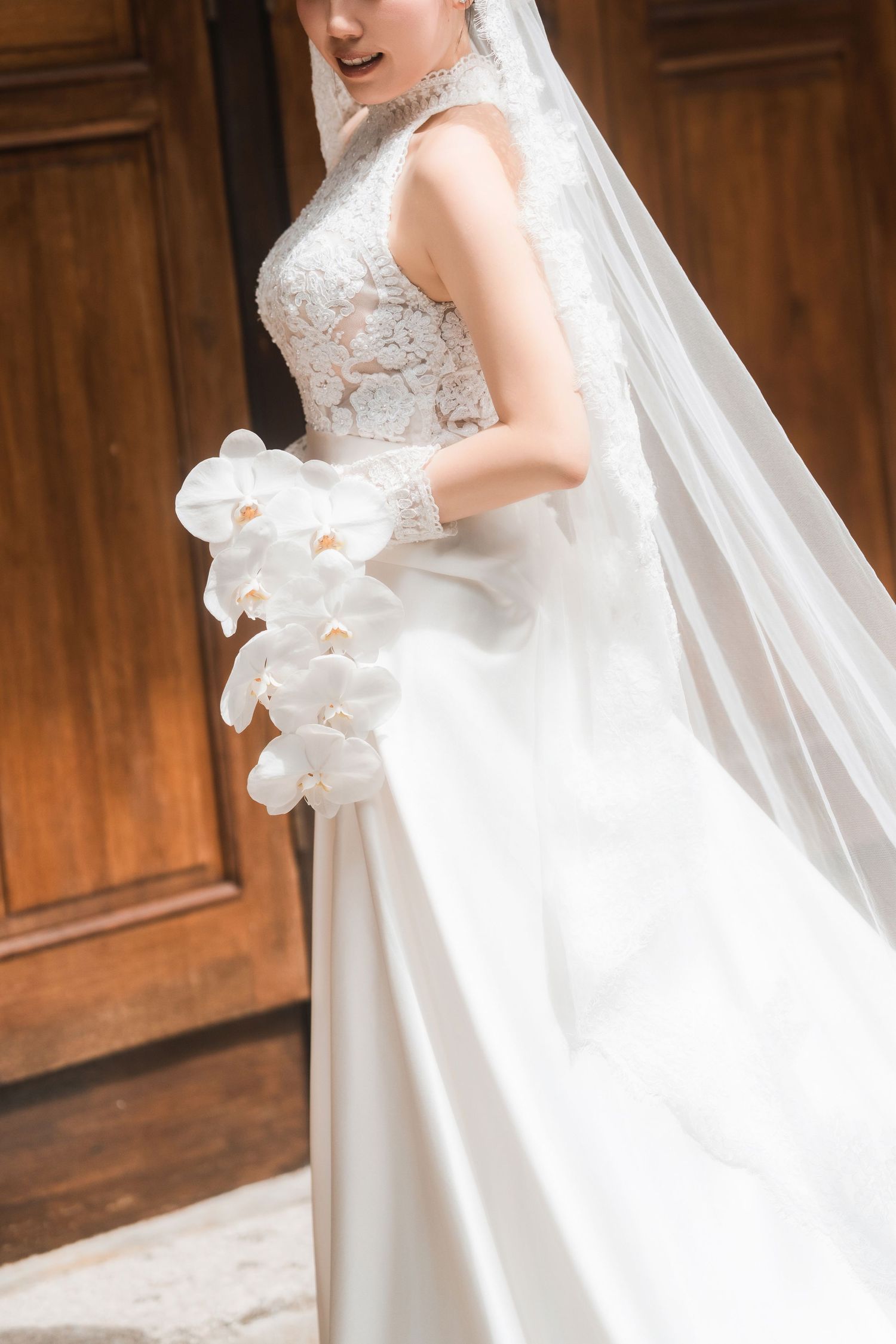Detailed view of an elegant white wedding gown with lace details and flowing veil.
