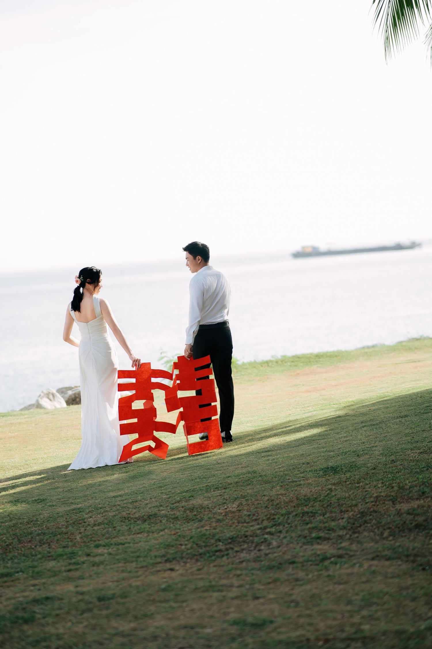 A couple sits together on red chairs overlooking a scenic coastal view.