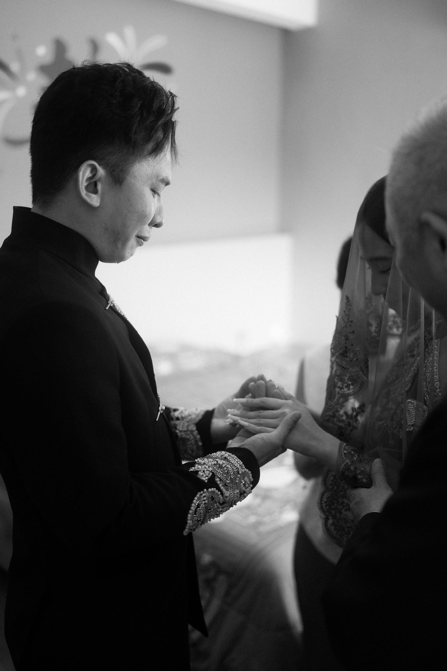 An emotional groom sheds tears of joy while holding his bride's hands at a traditional Penang wedding