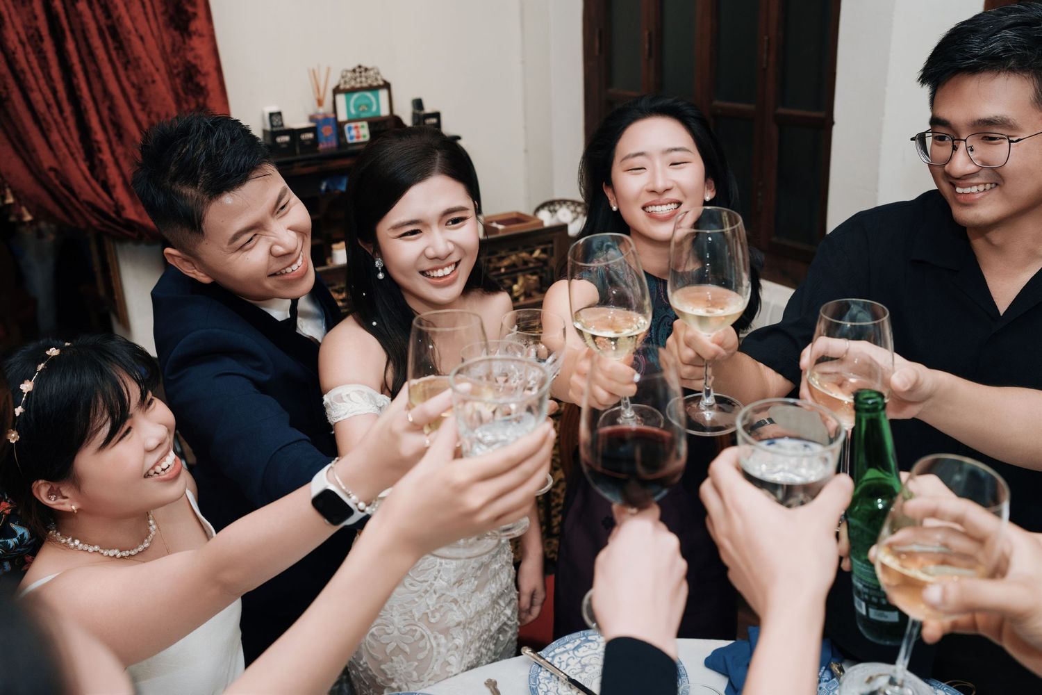 Happy wedding couple and friends raising glasses for a toast at Kebaya Dining Room