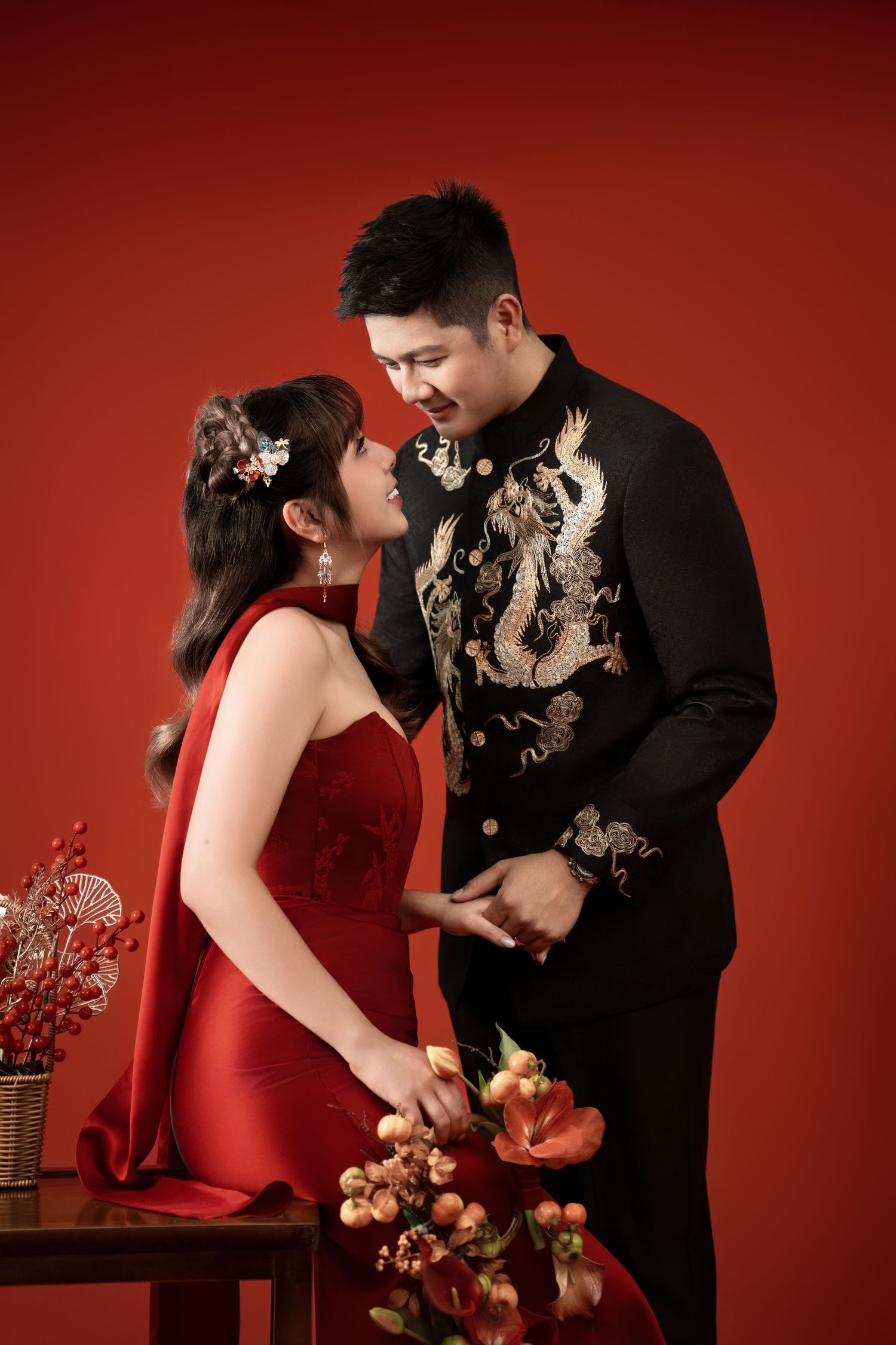 Intimate couple photos in red and black formal wear against dramatic red studio backdrop.
