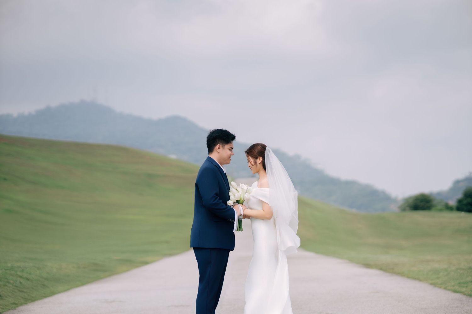 Elegant pre-wedding pose at Mengkuang Dam, Penang, with a minimalist mountain backdrop