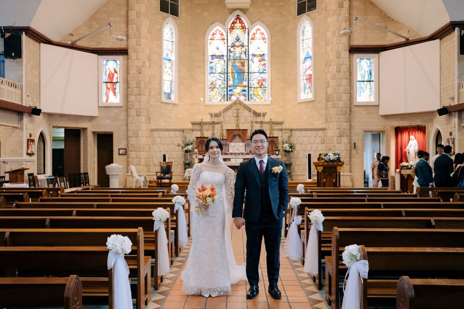 Symmetrical shot of a bride and groom standing in the center aisle of an empty church with high vaulted ceilings