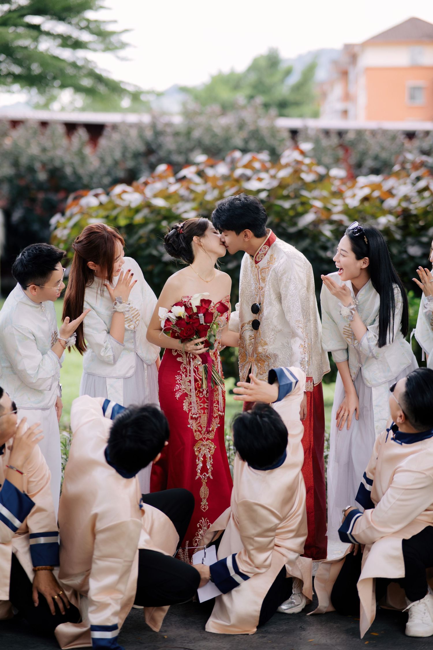 Wedding celebration with attendants in white and cream traditional attire gathered outdoors.