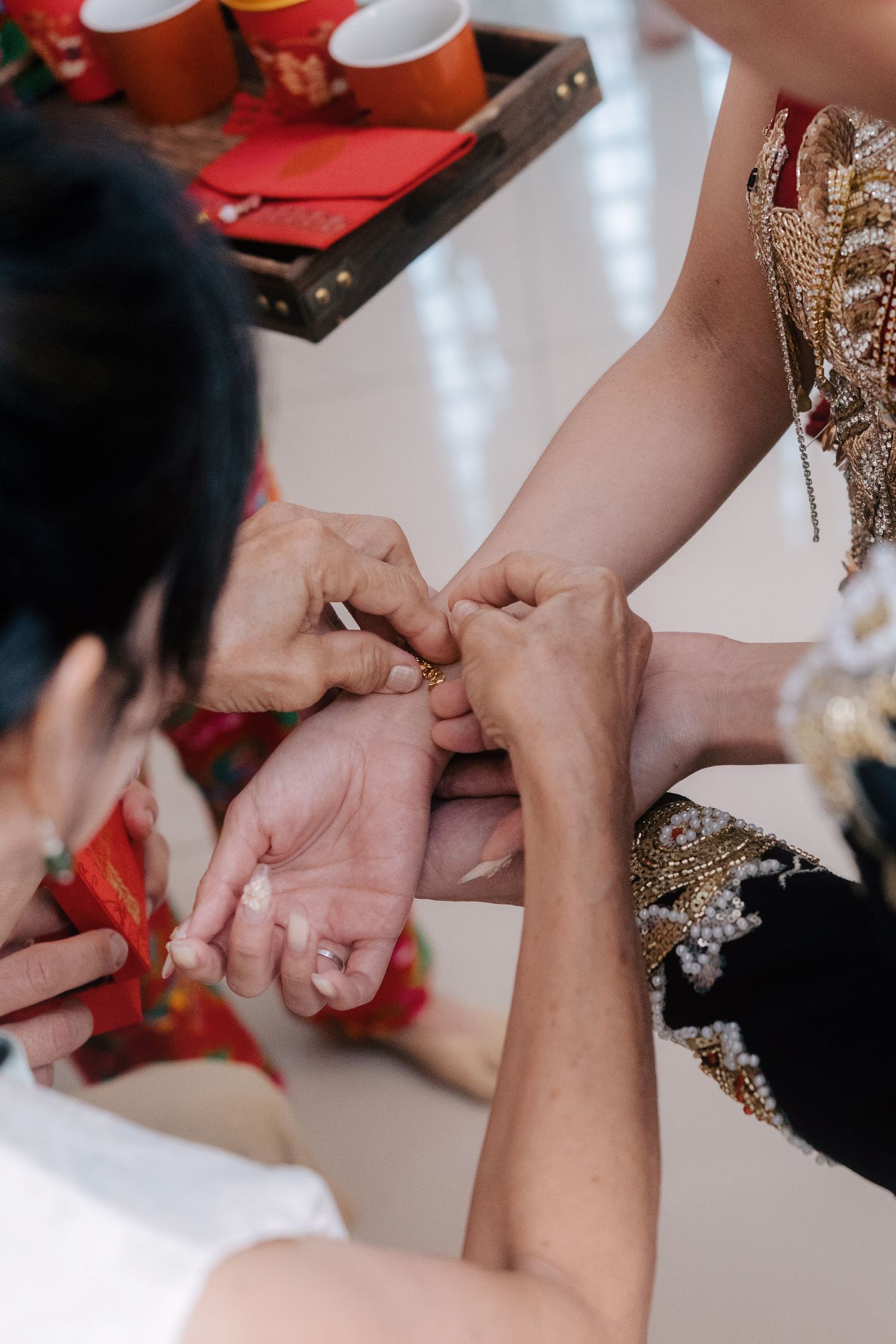 Bride's parent places a gold wedding bracelet on the bride's wrist, a common Chinese wedding tradition