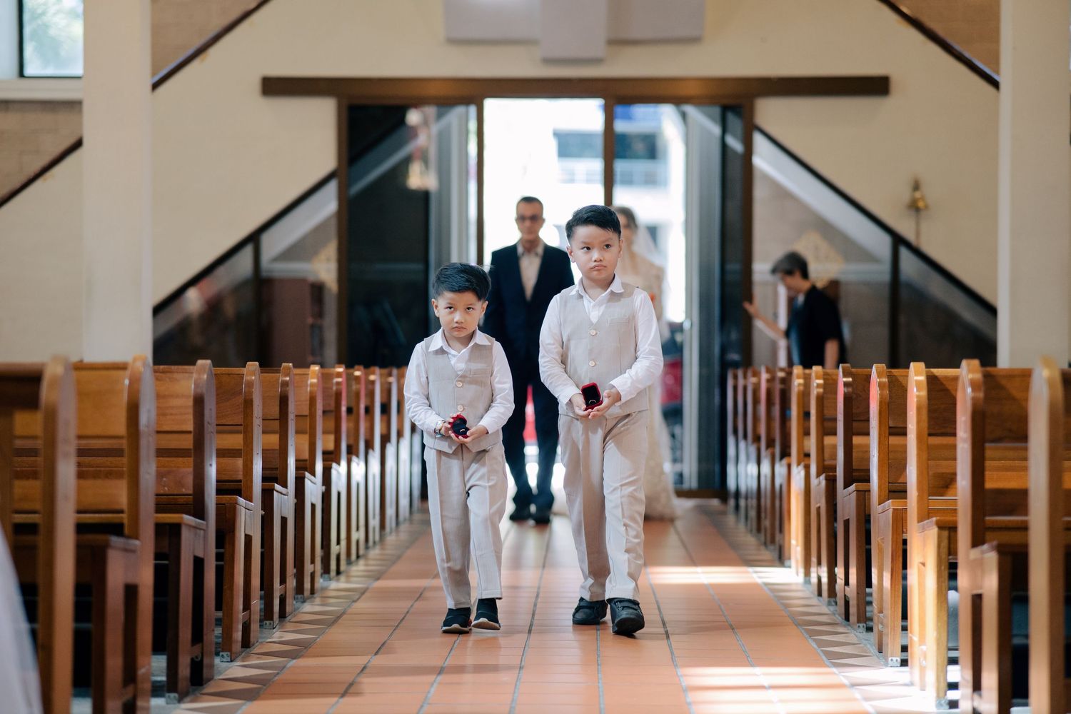Procession of ring bearers and the bride entering for a traditional church wedding ceremony in a stone chapel