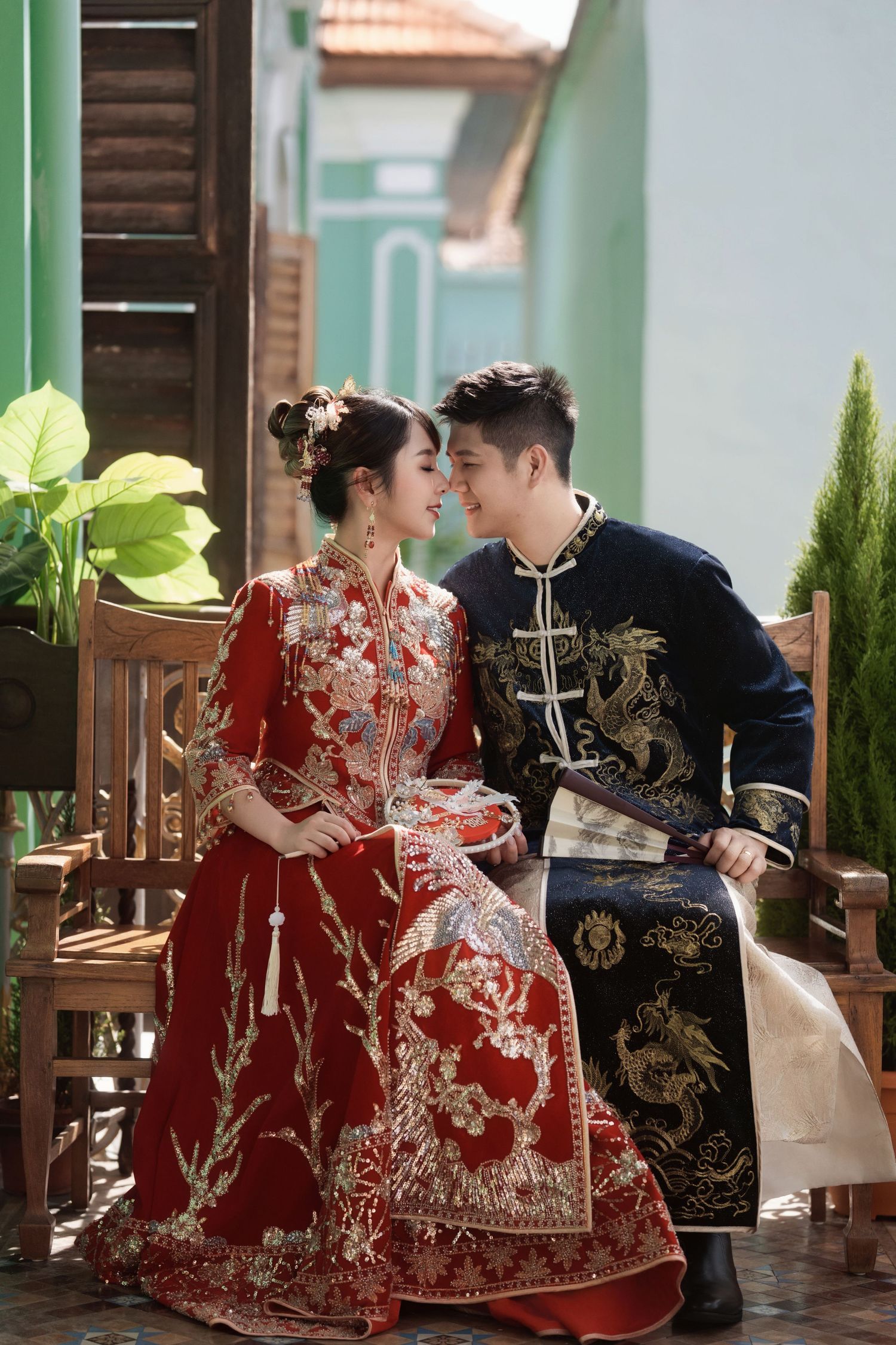 Detailed view of a red embroidered Kua wedding dress and groom's dragon robe during a Peranakan-themed bridal photoshoot