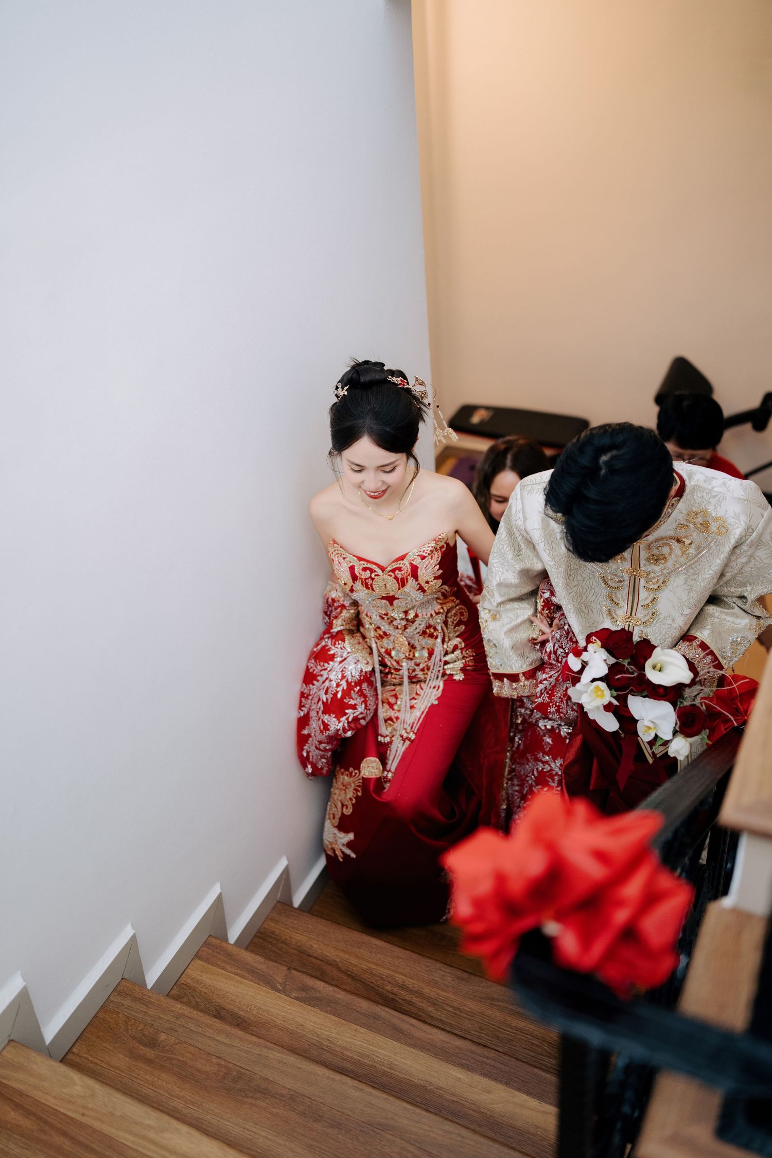 Red and white traditional wedding attire displayed on hangers in a dressing room.