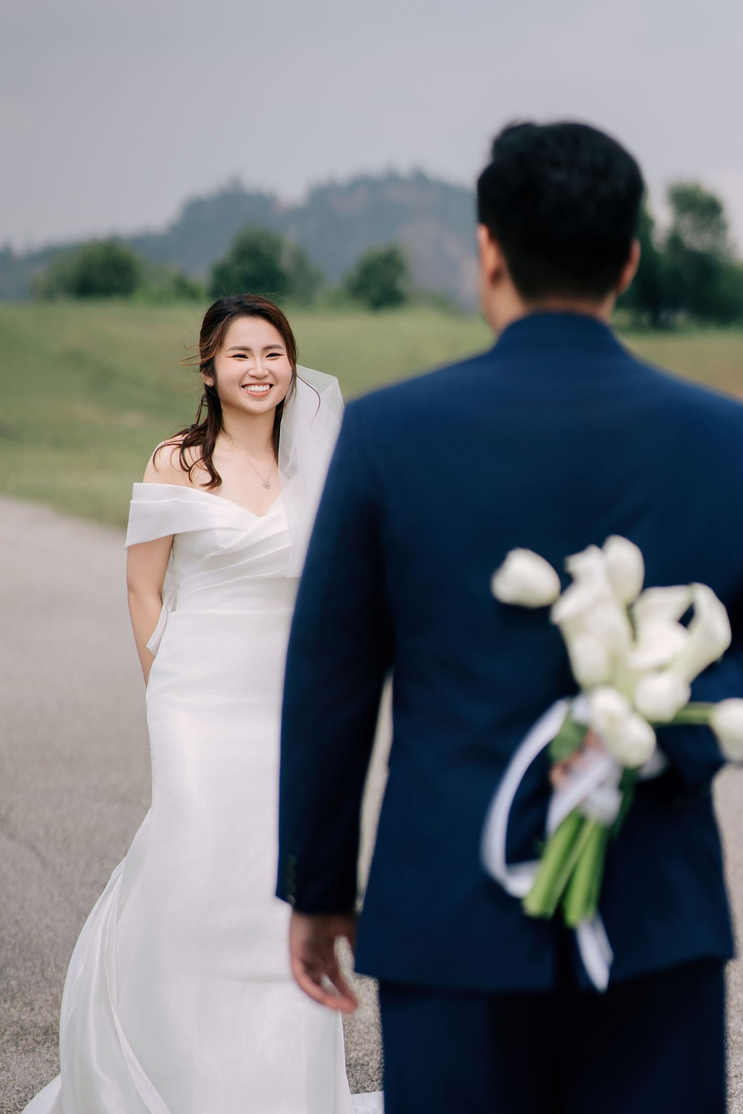 Wedding couple sharing a joyful moment on a rural road with flowers.