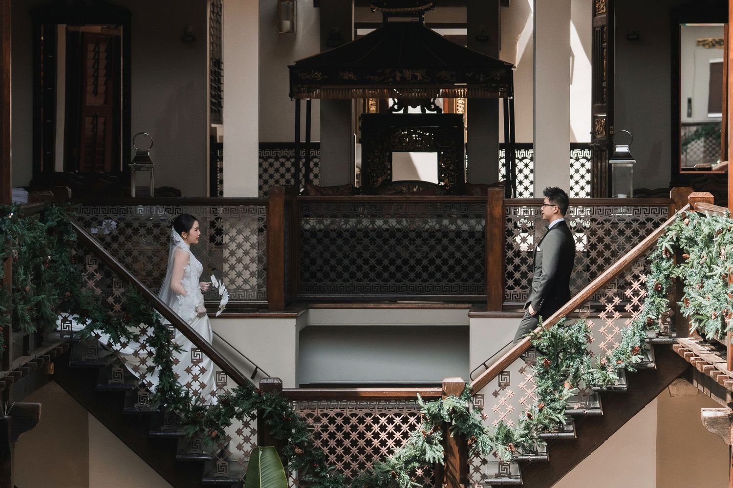 Luxury heritage wedding photography featuring a couple on ornate wooden stairs in a grand courtyard Seven Terraces Penang