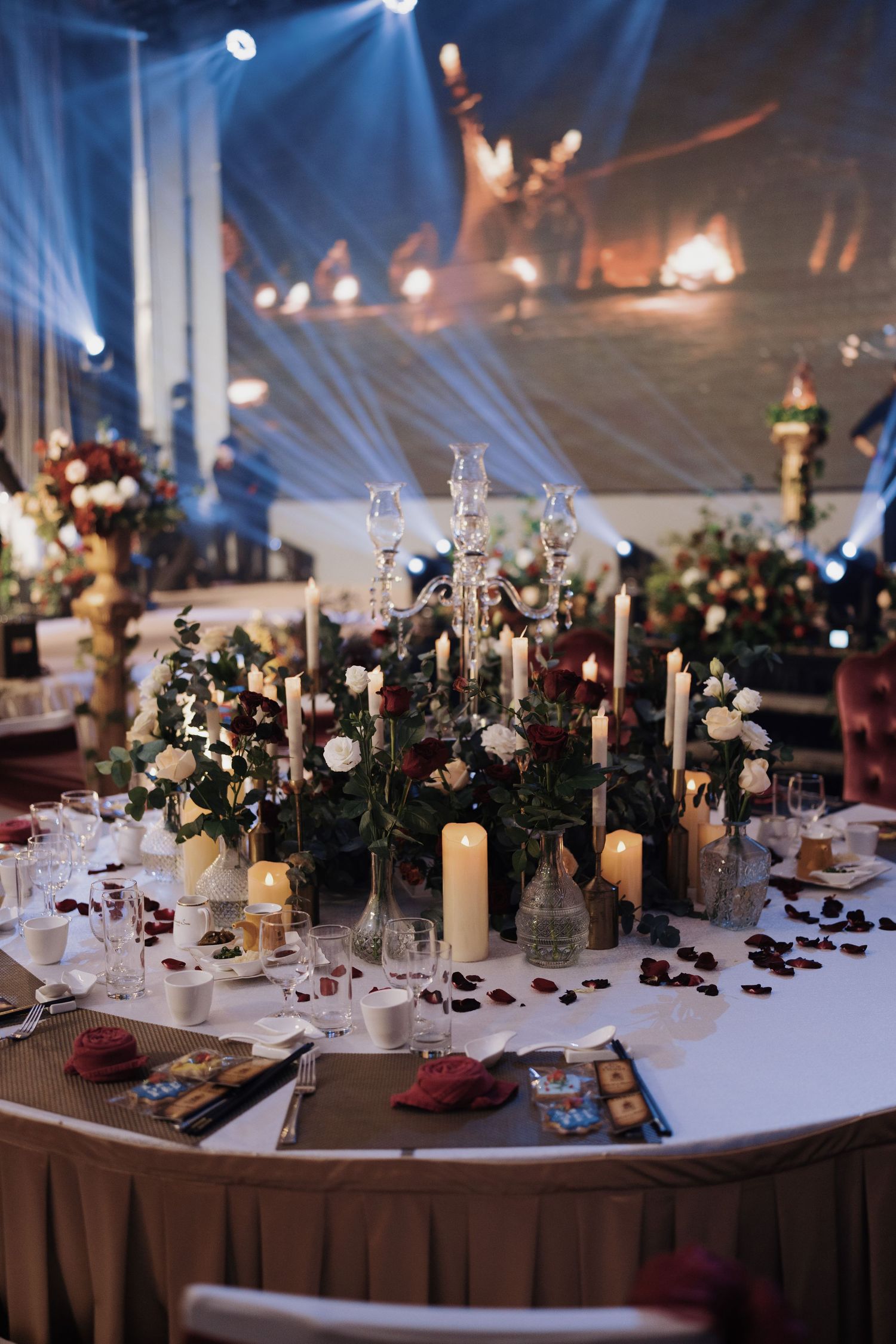Enchanted ballroom table setting featuring red rose centerpieces and warm candlelight at Olive Tree Hotel Grand Ballroom