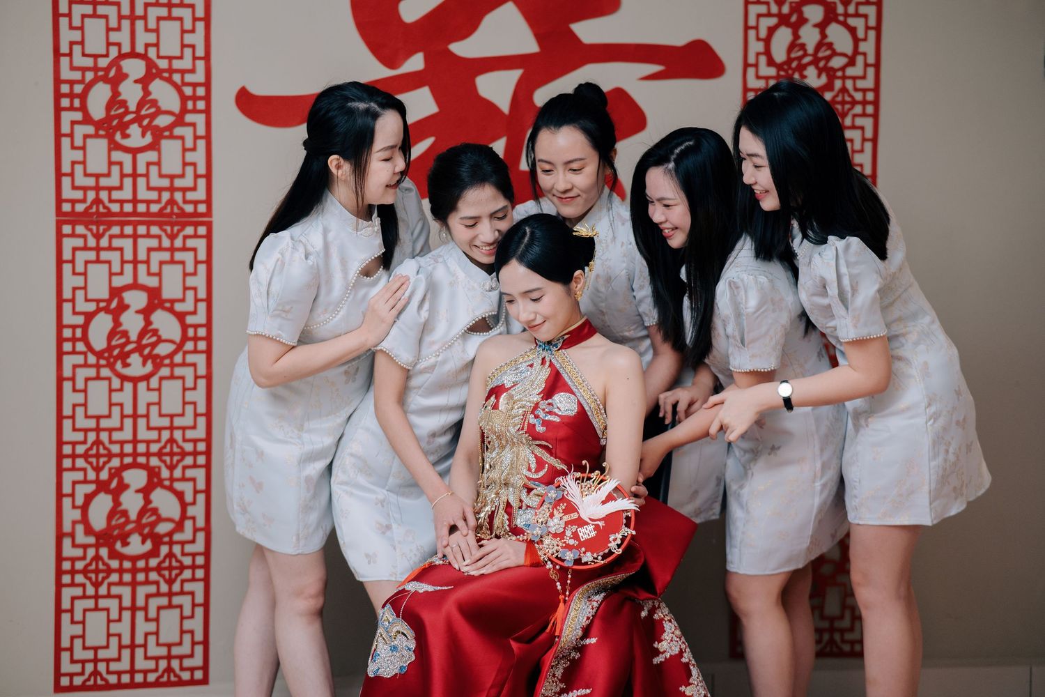 Five bridesmaids in matching light blue dresses surrounding the seated bride in her red Kua