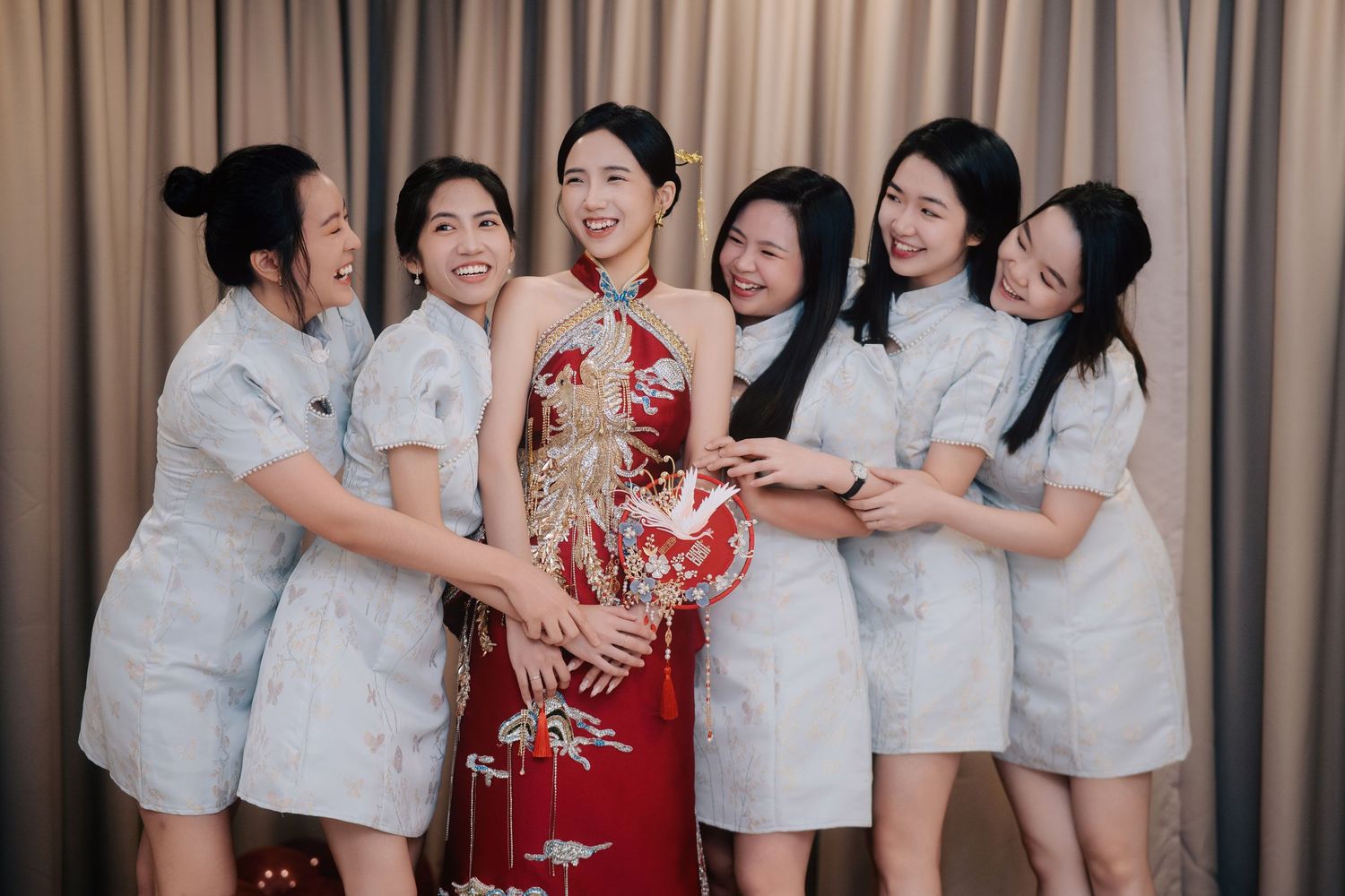 Joyful celebration with bridesmaids and a bride in her red Sangit at a Traditional Chinese Wedding