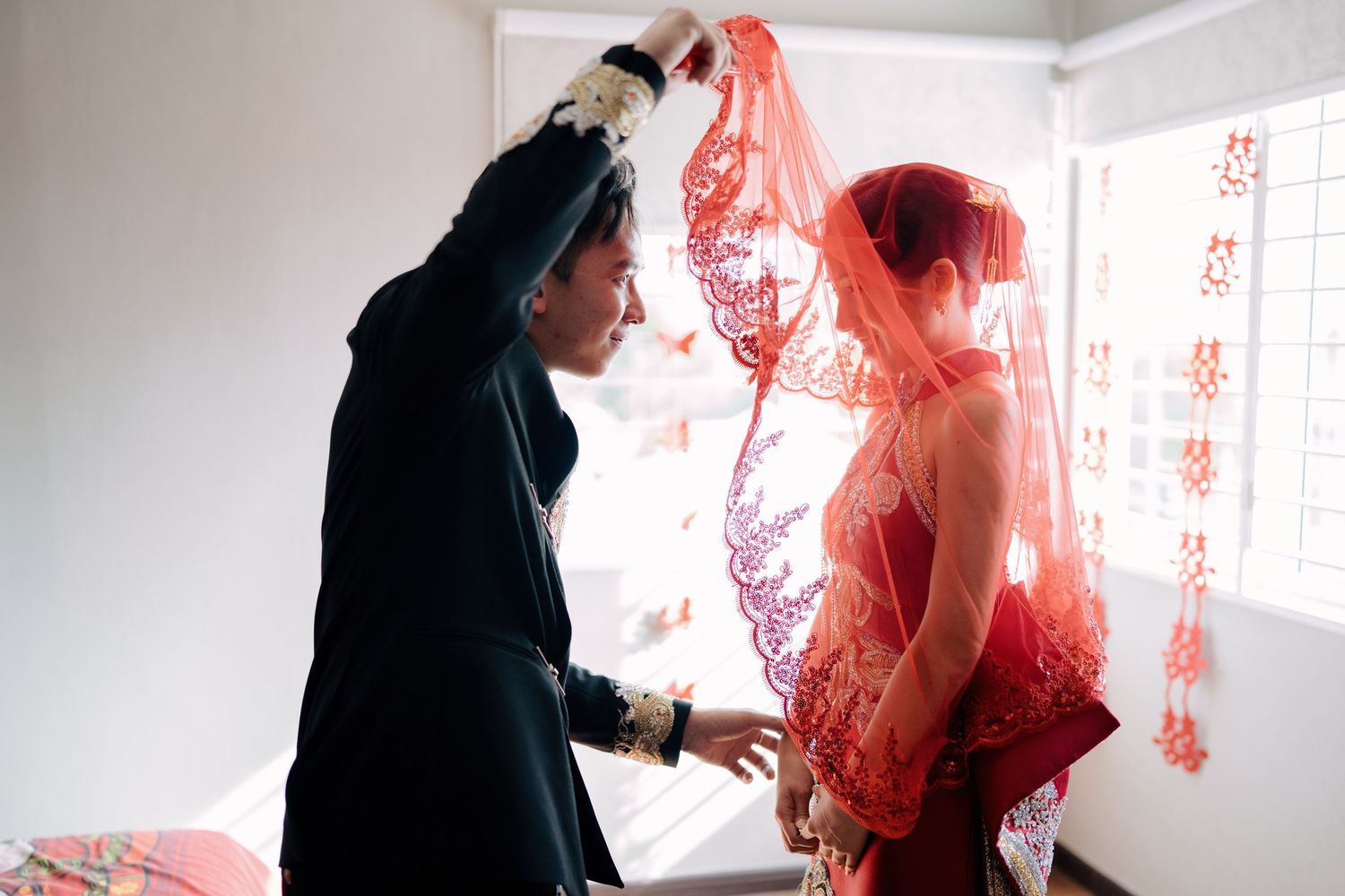 Groom performs the tradition of lifting the bride's red veil during a Chinese wedding celebration
