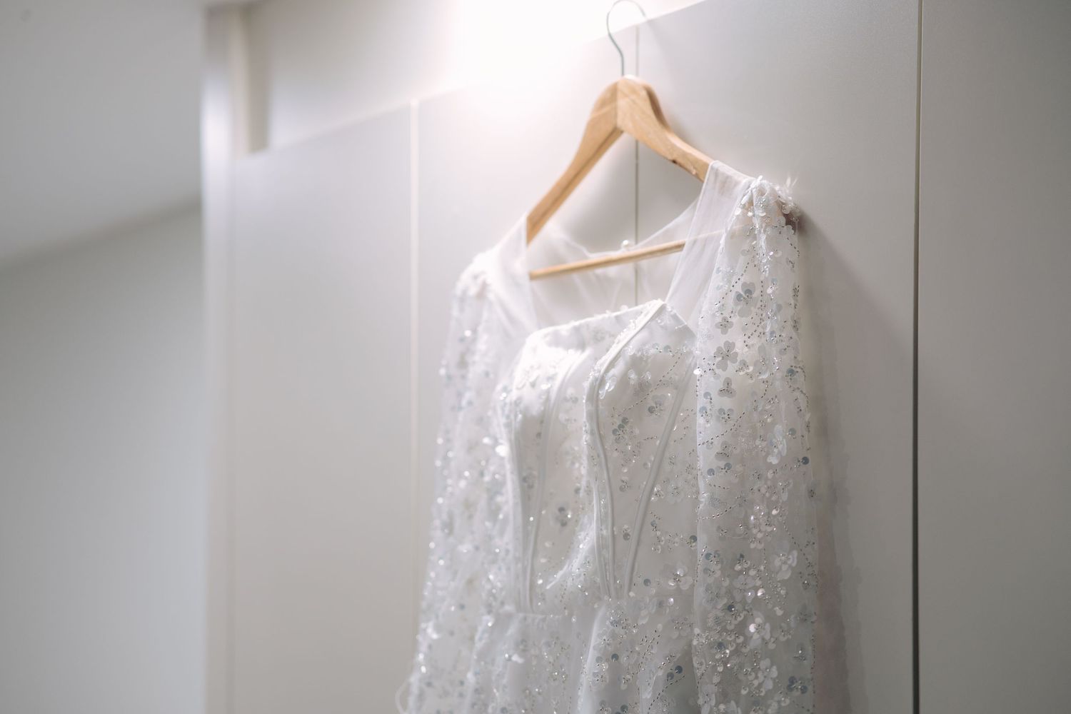 Detailed view of a sequin long sleeve wedding dress featuring shimmering floral appliqués and a corset-style bodice